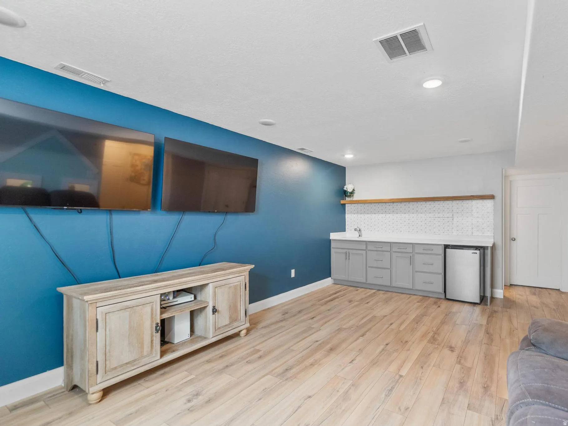 Unfurnished living room featuring light wood-type flooring and bar with sink