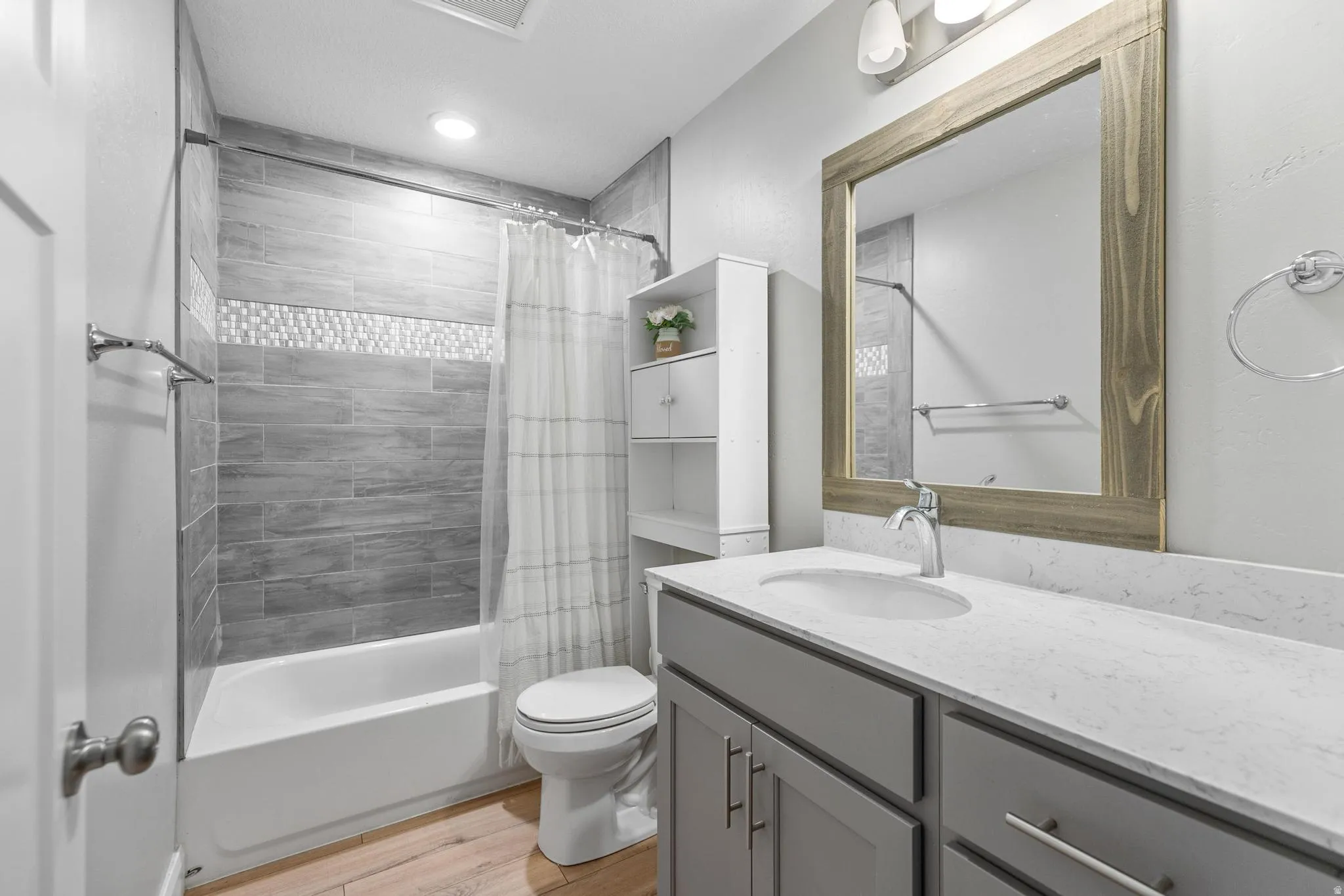 Full bathroom featuring vanity, shower / tub combo, and light wood-style floors