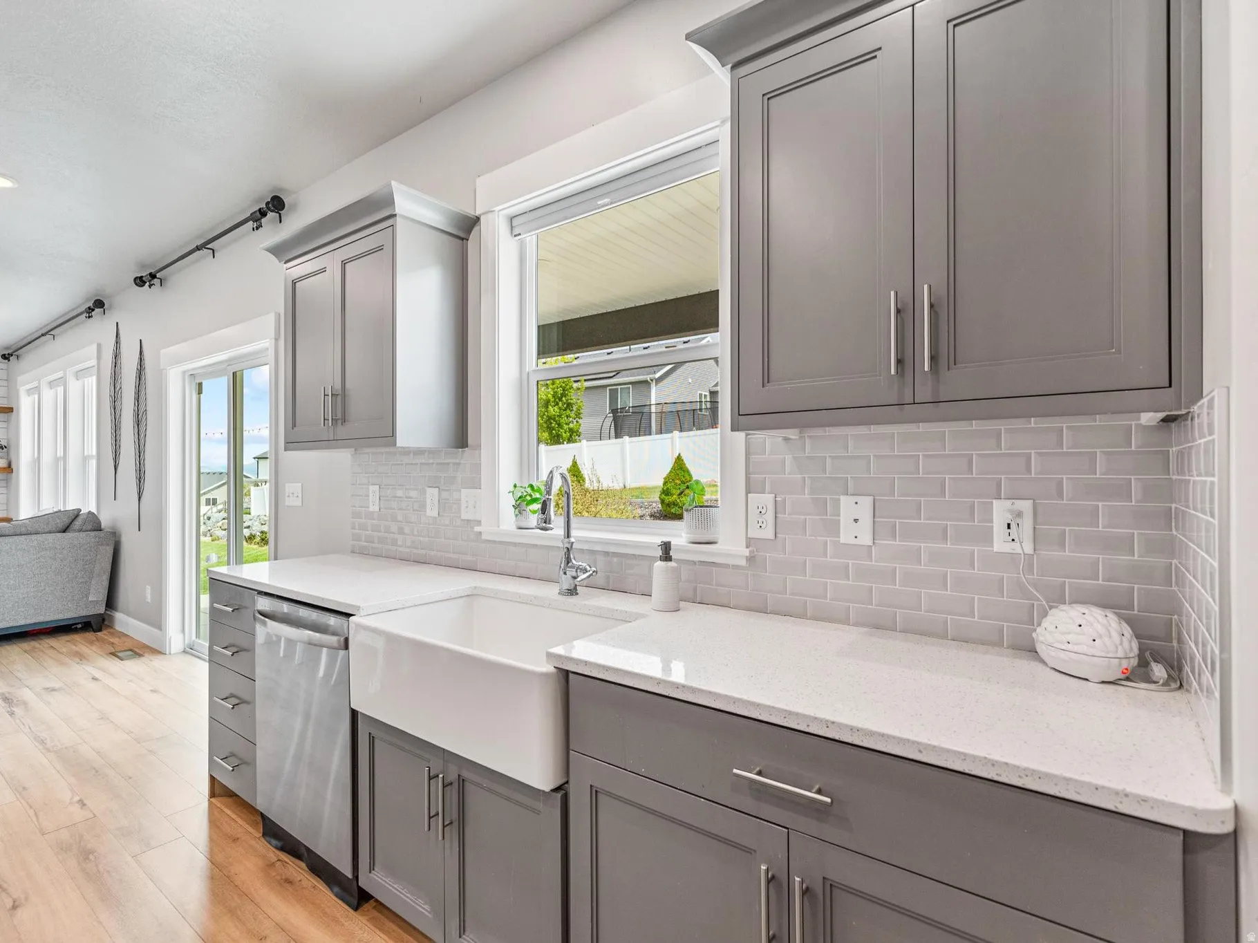 Kitchen featuring gray cabinets, light stone countertops, light wood-style floors, open floor plan, and dishwasher