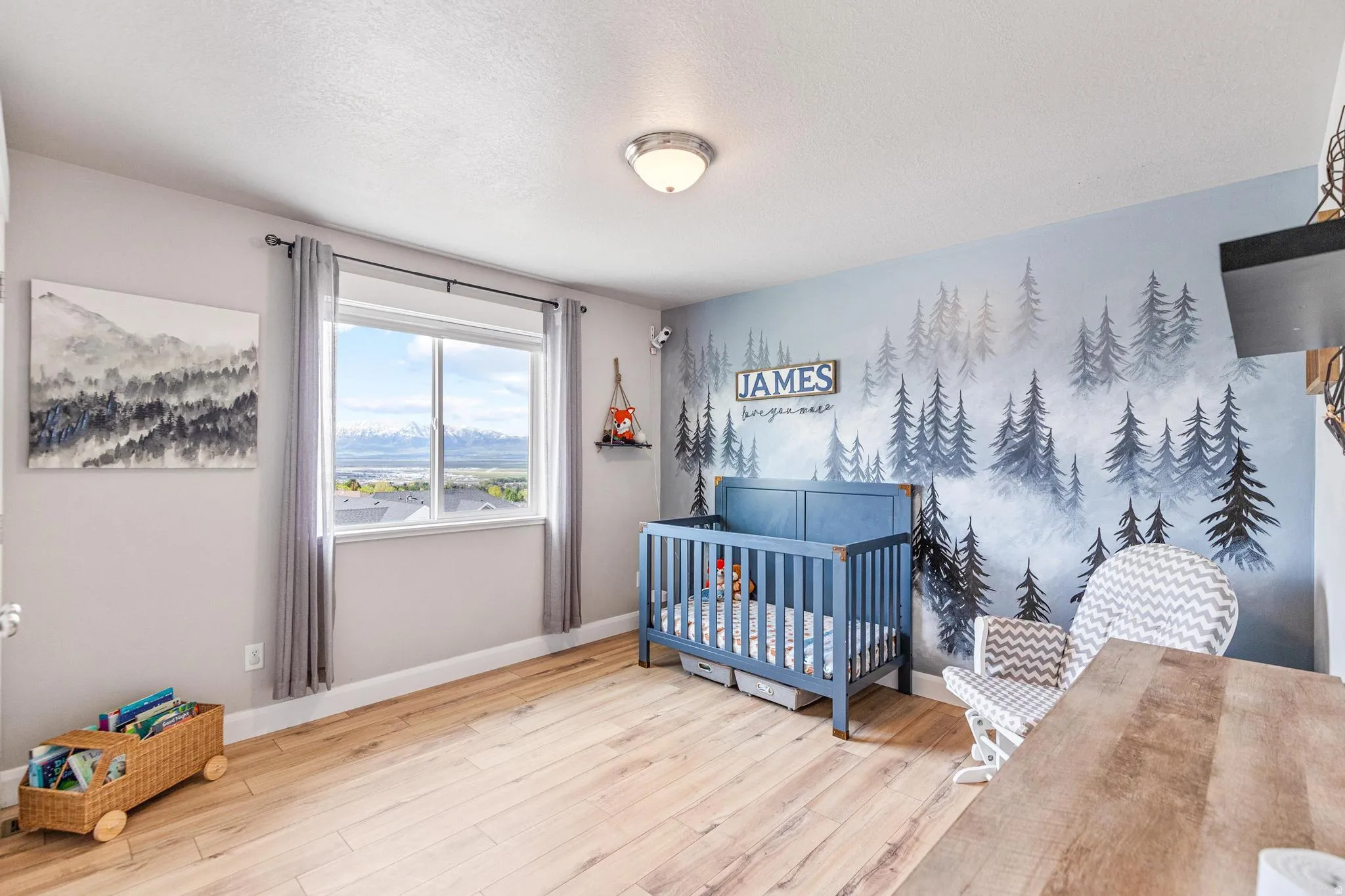Bedroom with a nursery area, hardwood / wood-style floors, a textured ceiling, and a mountain view