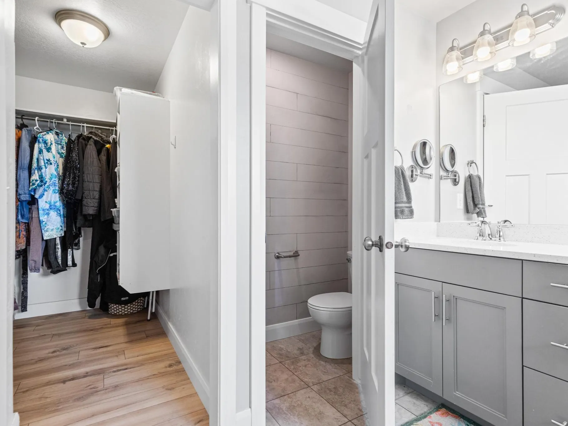 Bathroom featuring vanity, a walk in closet, and light wood-style flooring