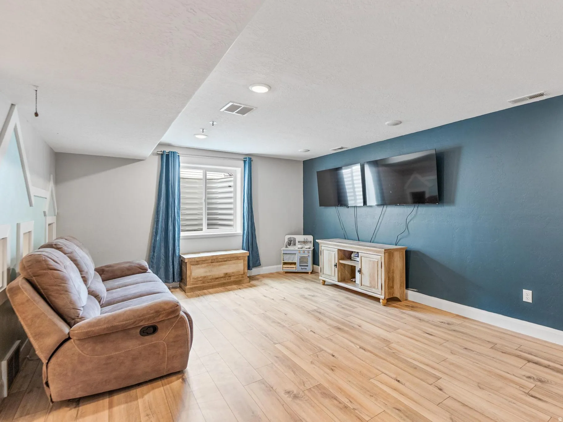 Living area with light wood-type flooring and a textured ceiling