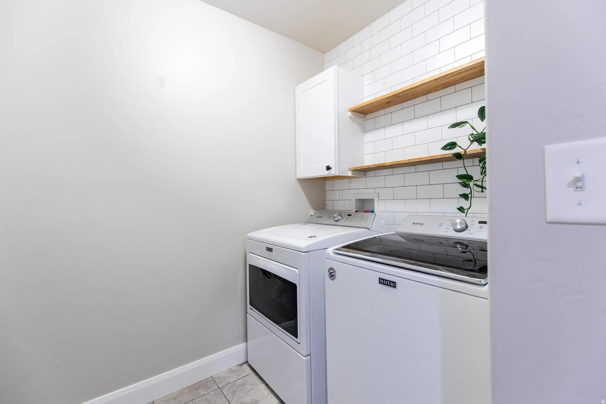Laundry room with washer and clothes dryer, cabinet space, and light tile patterned floors