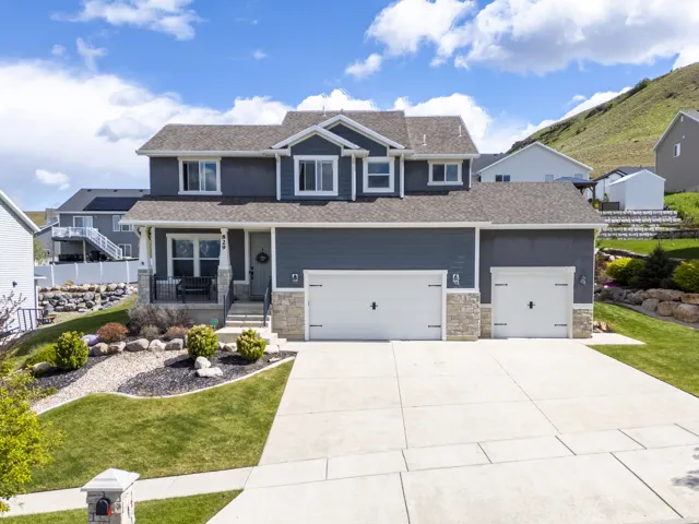 Craftsman-style house with covered porch, an attached garage, concrete driveway, stone siding, and a front lawn