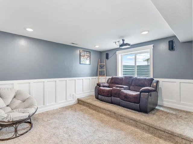 Living area featuring a decorative wall, wainscoting, carpet floors, and recessed lighting