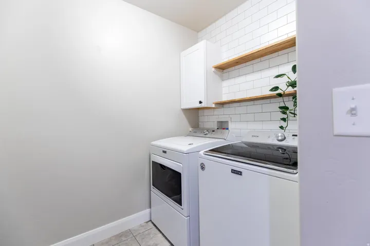 Laundry room with washer and clothes dryer, cabinet space, and light tile patterned floors