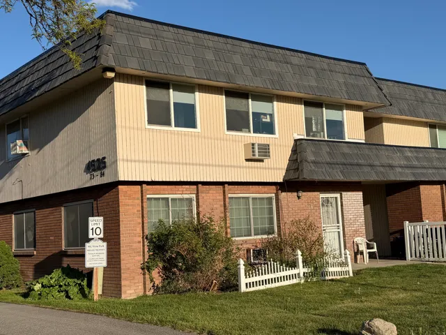 View of front of home with mansard roof and a wall unit AC