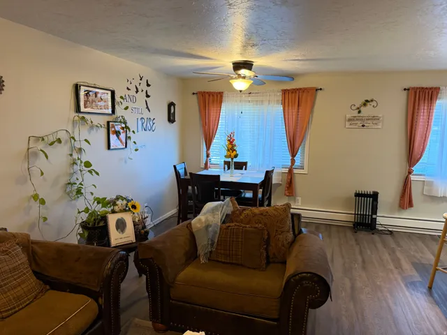 Dining space with a textured ceiling, dark wood finished floors, ceiling fan, and a baseboard heating unit