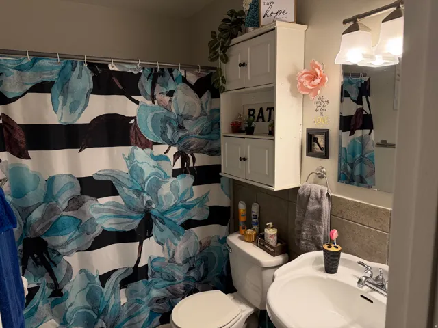 Full bathroom with tile walls and a shower with shower curtain