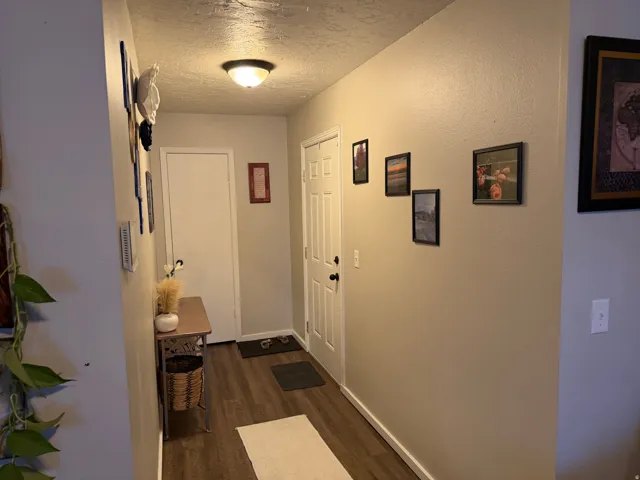 Doorway featuring a textured ceiling and wood finished floors