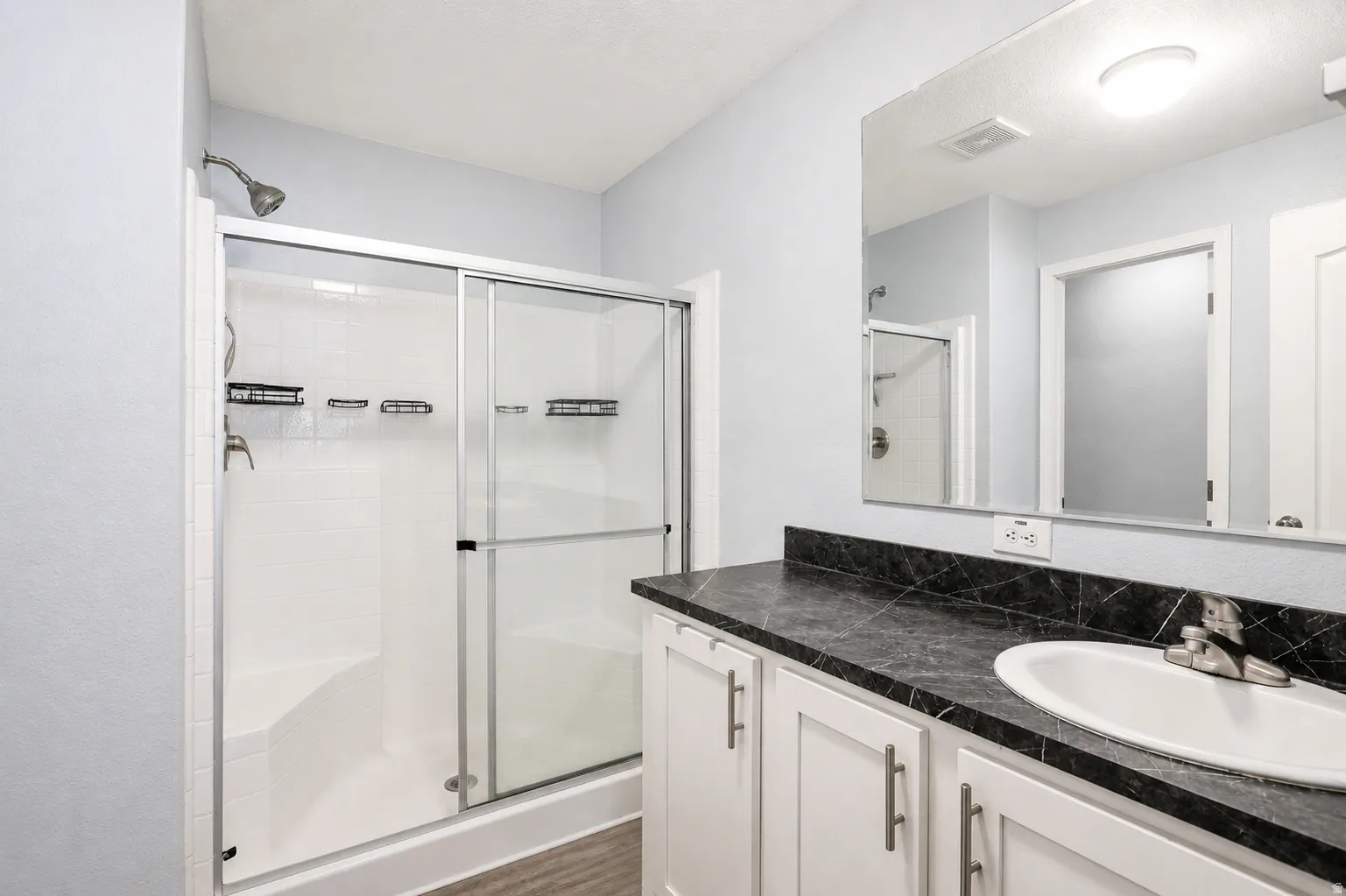 Full bath featuring vanity, a stall shower, and dark wood finished floors