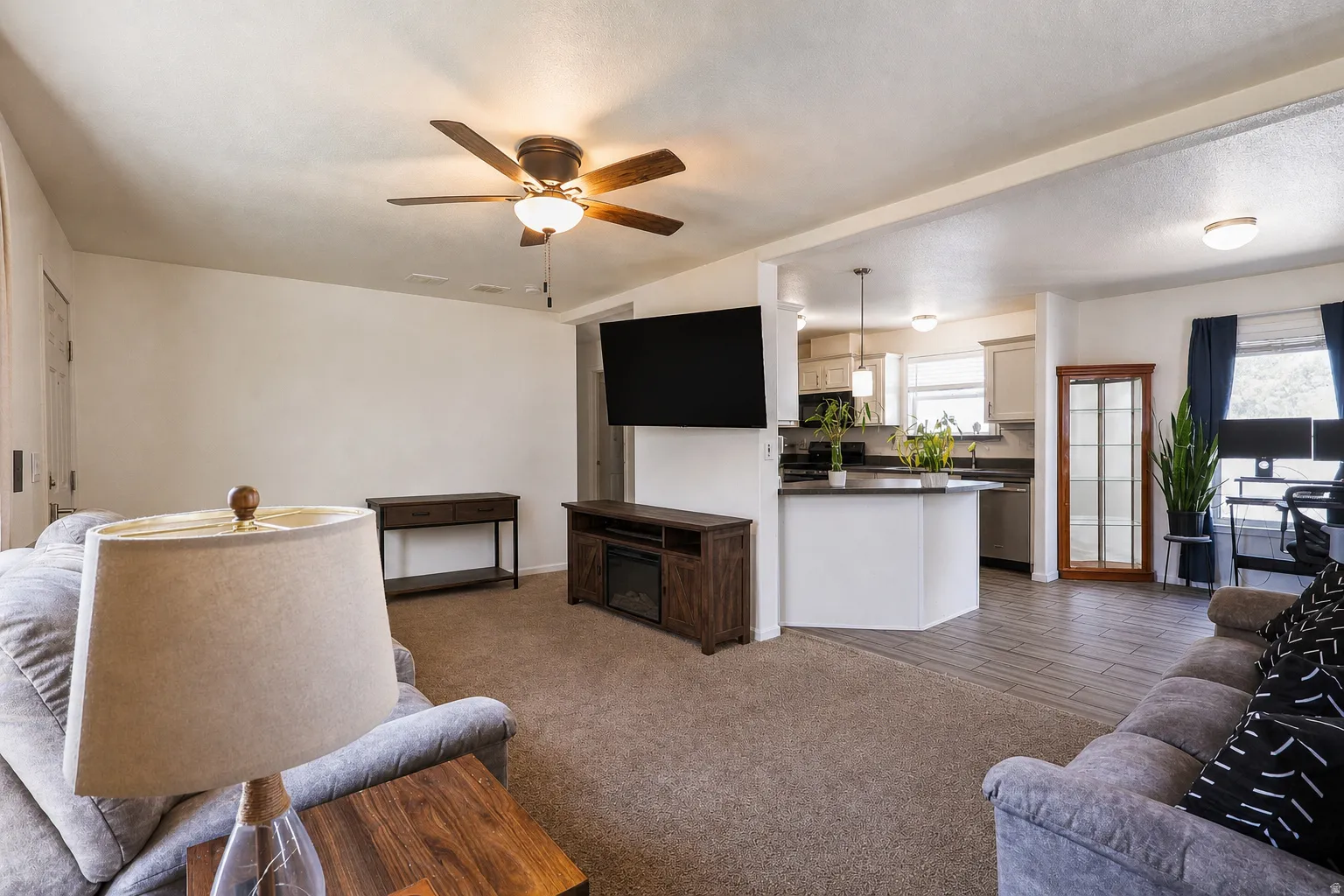 Living area with ceiling fan and dark carpet