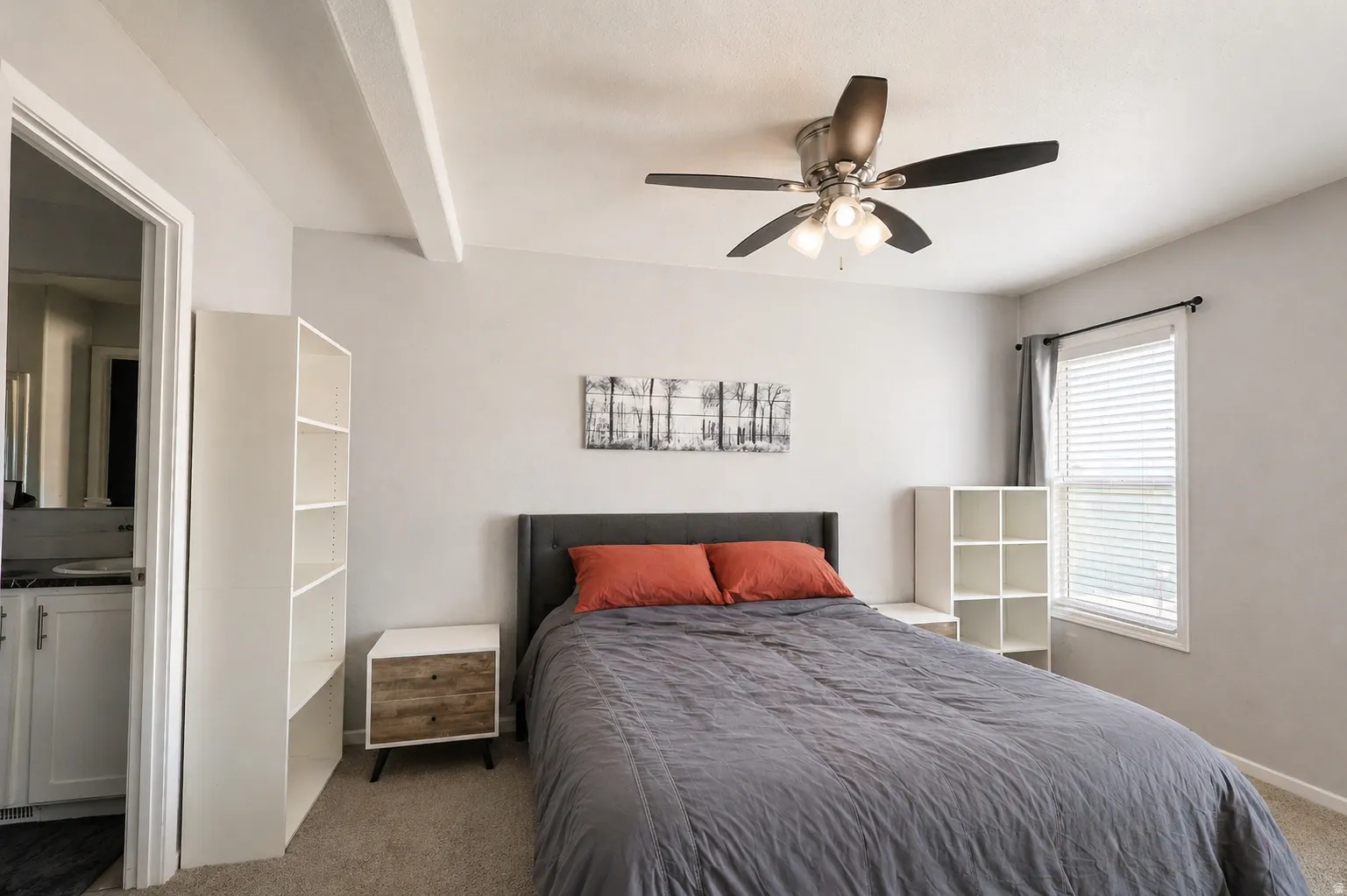 Carpeted bedroom featuring a ceiling fan and beamed ceiling