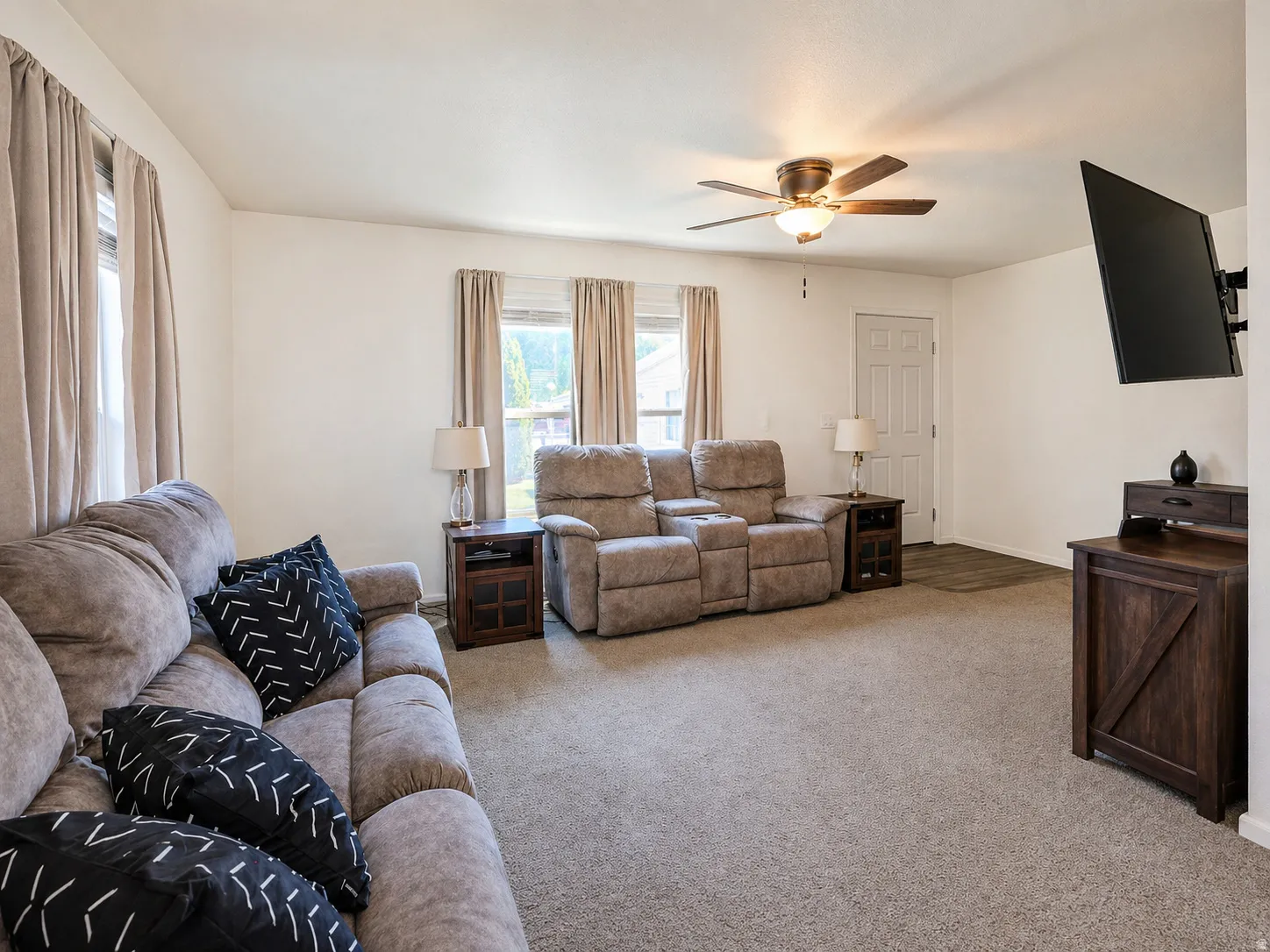 Living room with a ceiling fan and light carpet