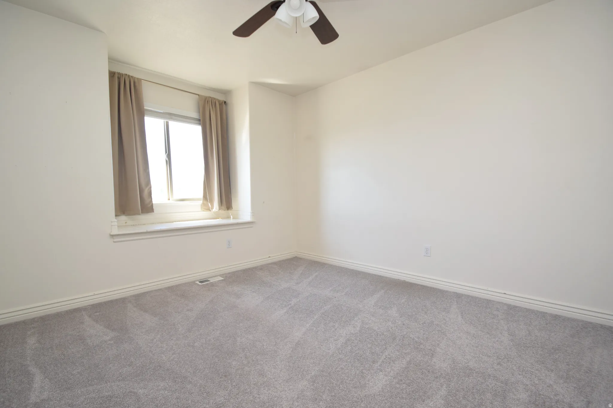 Carpeted spare room featuring baseboards and ceiling fan