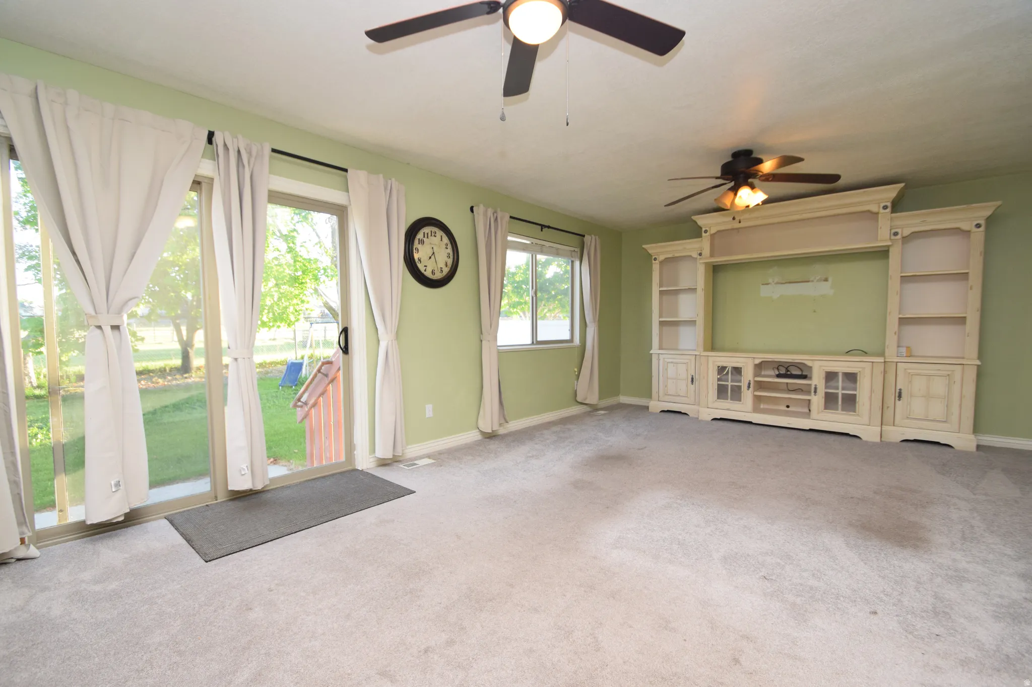 Unfurnished living room featuring carpet and a ceiling fan