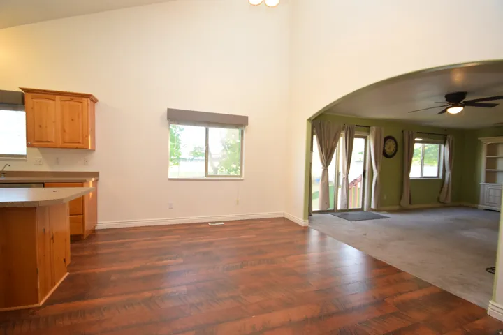Kitchen with open floor plan, a ceiling fan, arched walkways, dark wood-style floors, and lofted ceiling