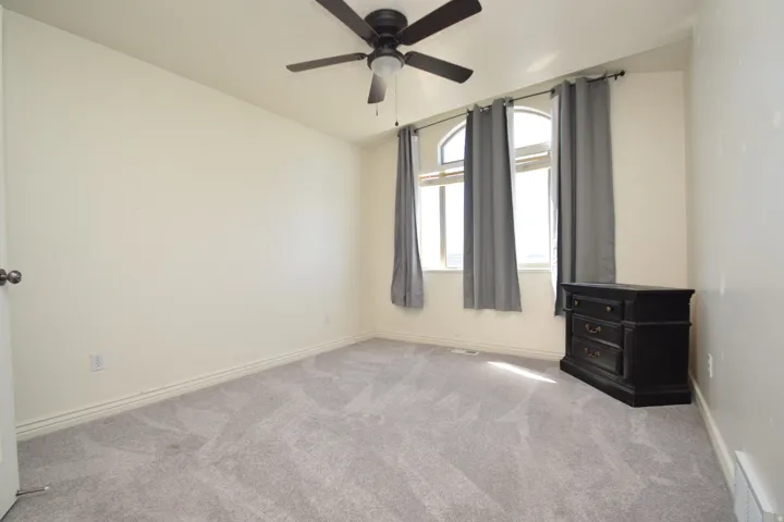 Empty room with light carpet, lofted ceiling, and ceiling fan