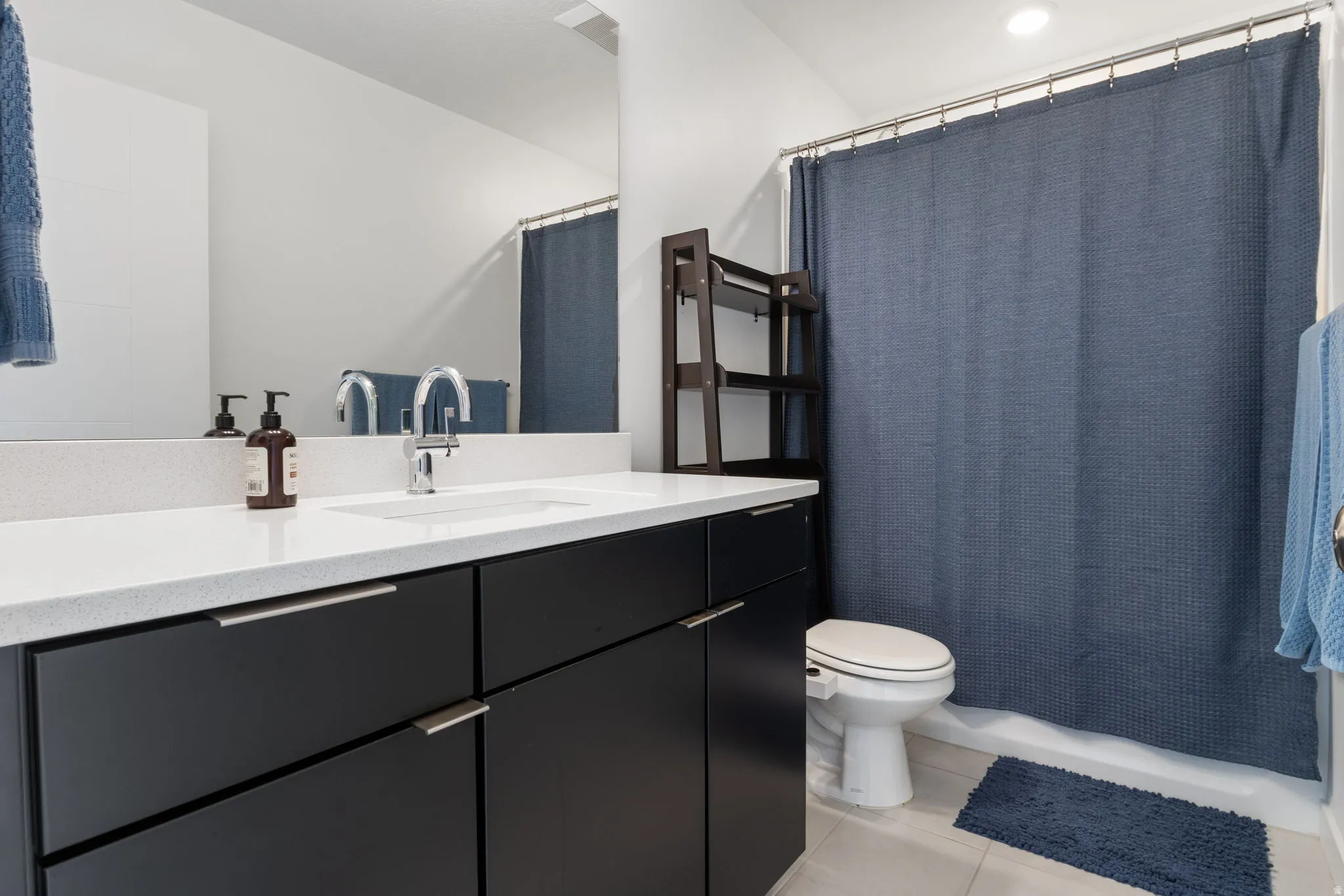 Full bath with vanity, light tile patterned floors, and shower / tub combo