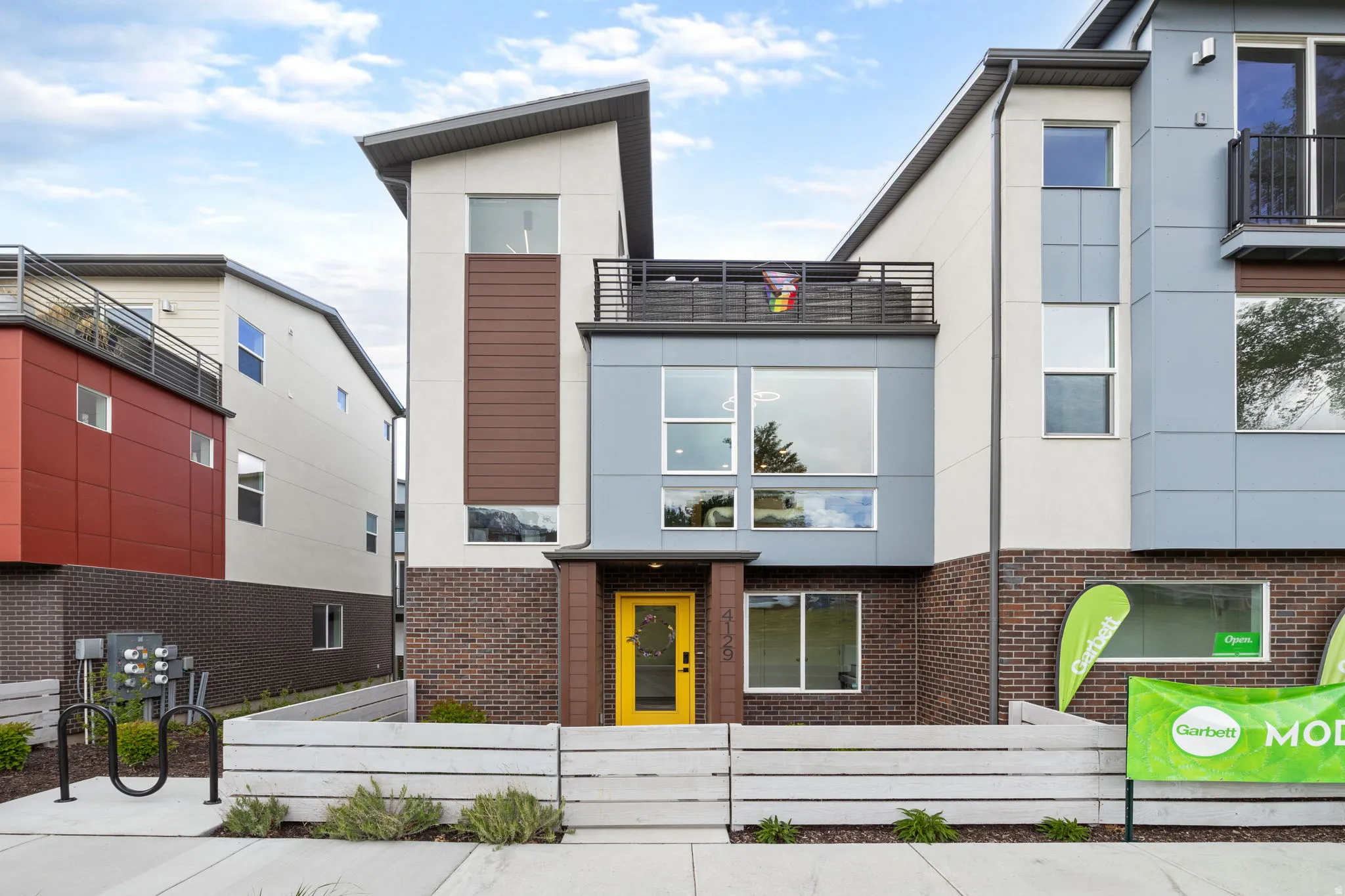 View of front facade featuring brick siding, stucco siding, and a fenced front yard