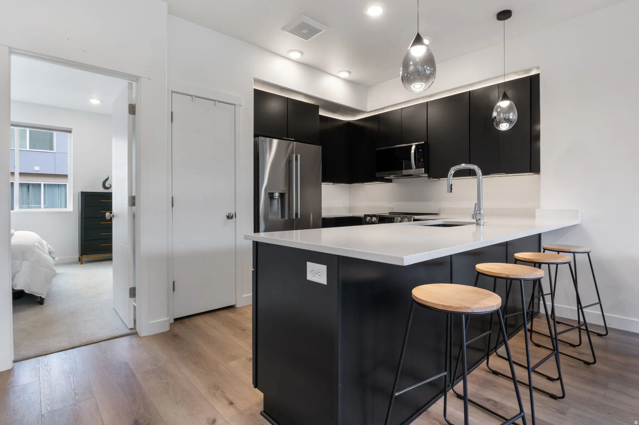 Kitchen featuring dark cabinetry, a breakfast bar, pendant lighting, a peninsula, and light wood-style floors