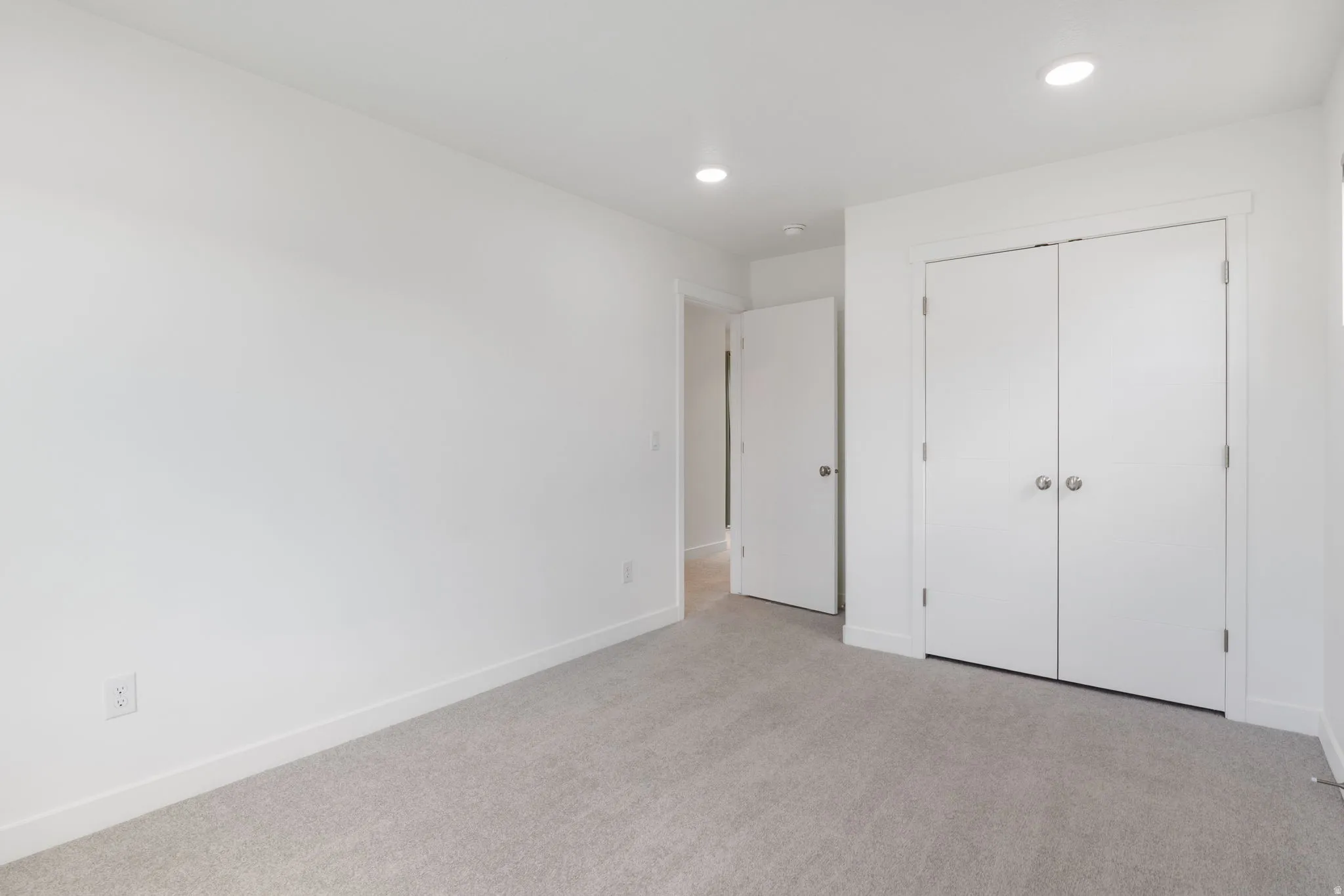 Unfurnished bedroom with light colored carpet, recessed lighting, and a closet