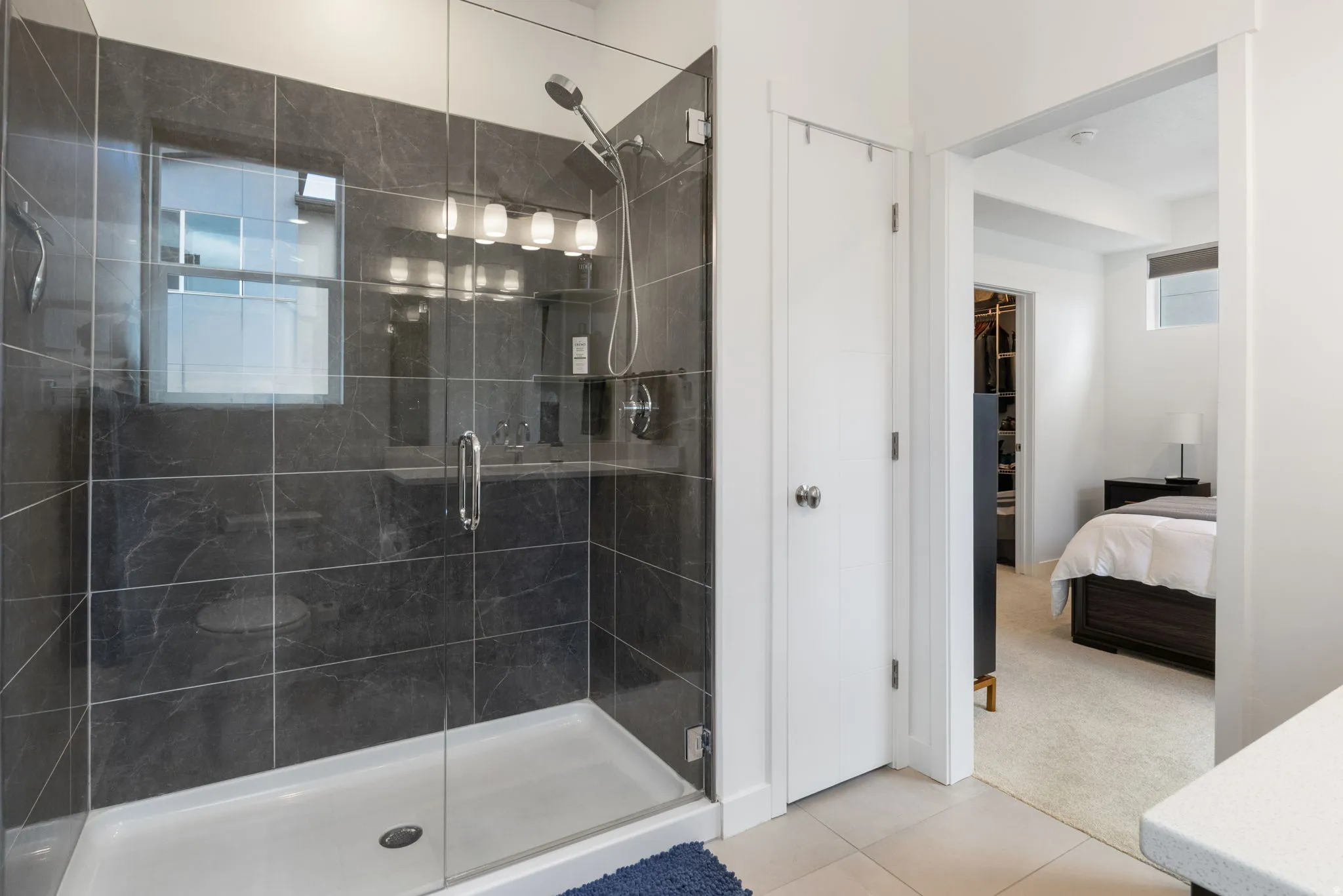 Ensuite bathroom with light carpet, vanity, a shower stall, and light tile patterned floors