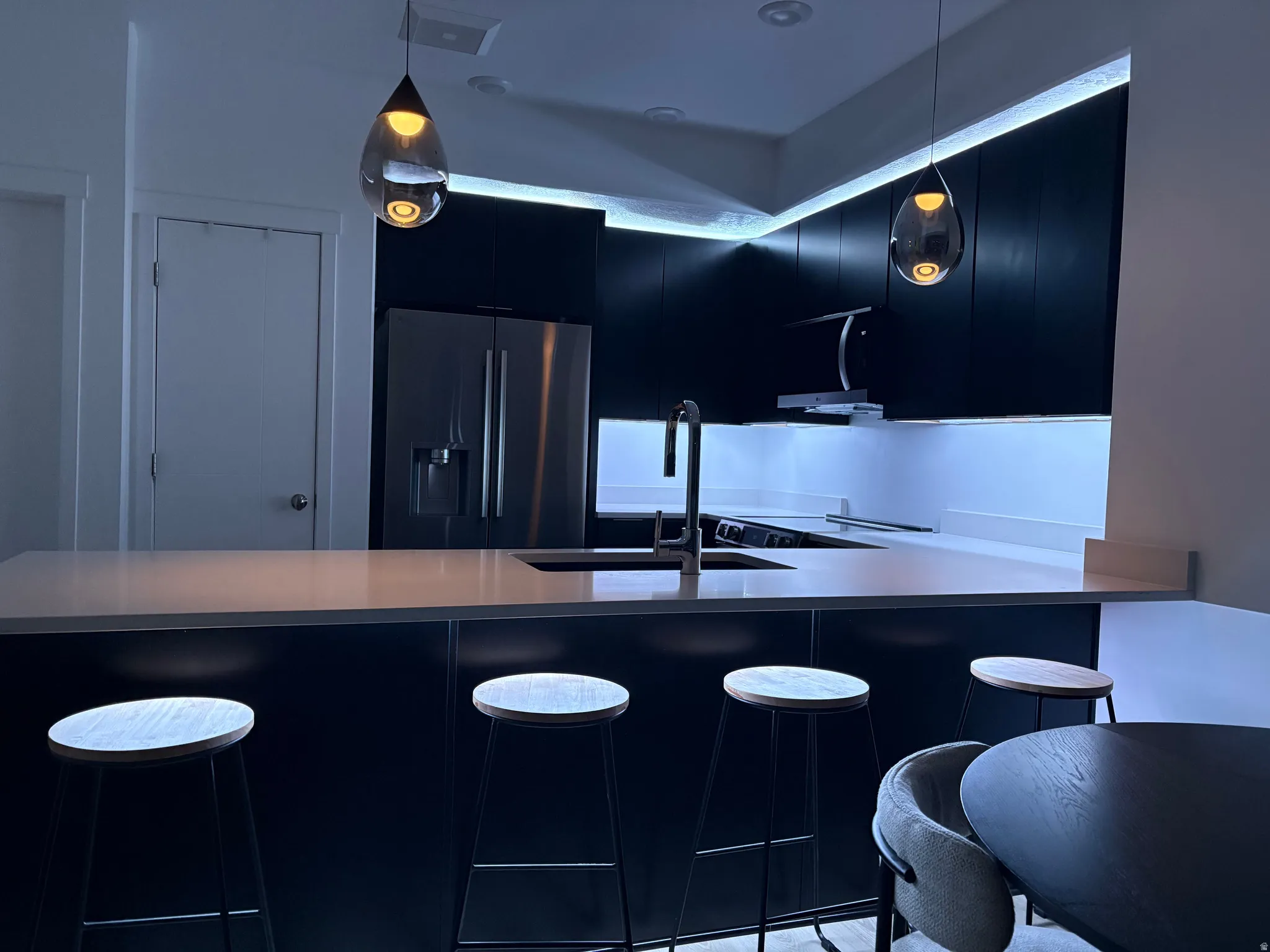 Kitchen with dark cabinets, fridge with ice dispenser, a breakfast bar area, and modern cabinets