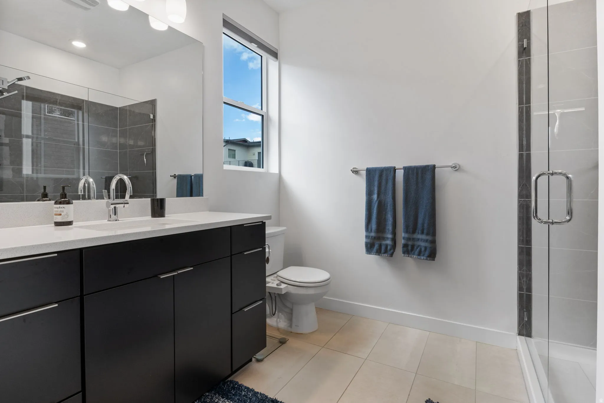 Full bath featuring a shower stall, vanity, and light tile patterned flooring