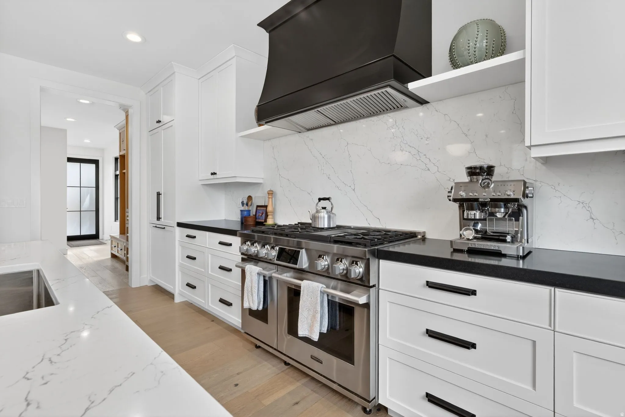 Kitchen featuring light wood finished floors, range with two ovens, white cabinetry, recessed lighting, and dark stone countertops