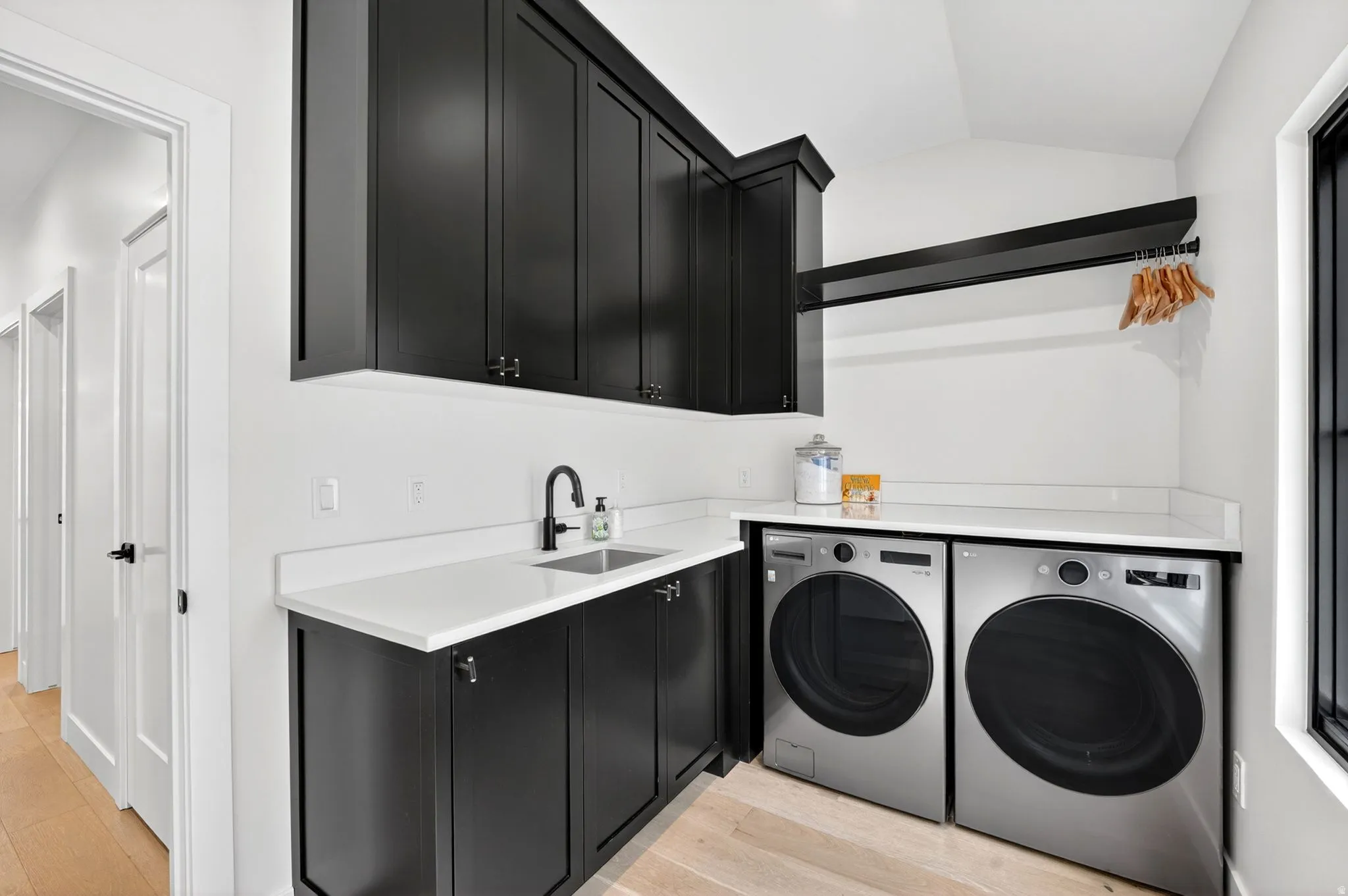 Laundry room featuring vaulted ceiling, light wood-style floors, washing machine and dryer, and cabinet space