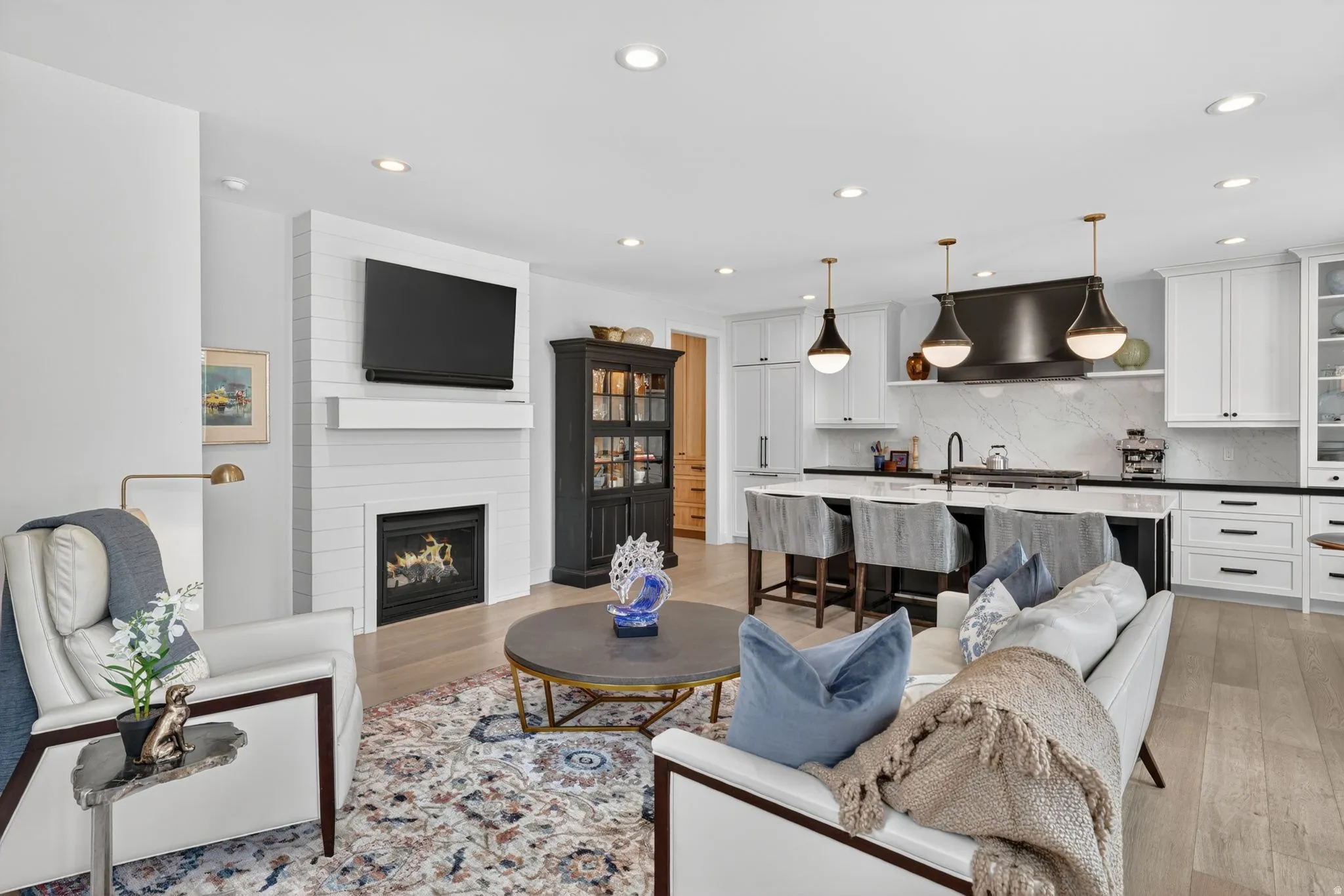 Living room with light wood finished floors, a large fireplace, and recessed lighting