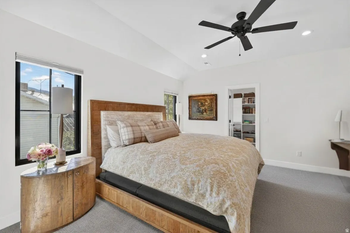 Bedroom with a spacious closet, carpet flooring, a ceiling fan, vaulted ceiling, and recessed lighting