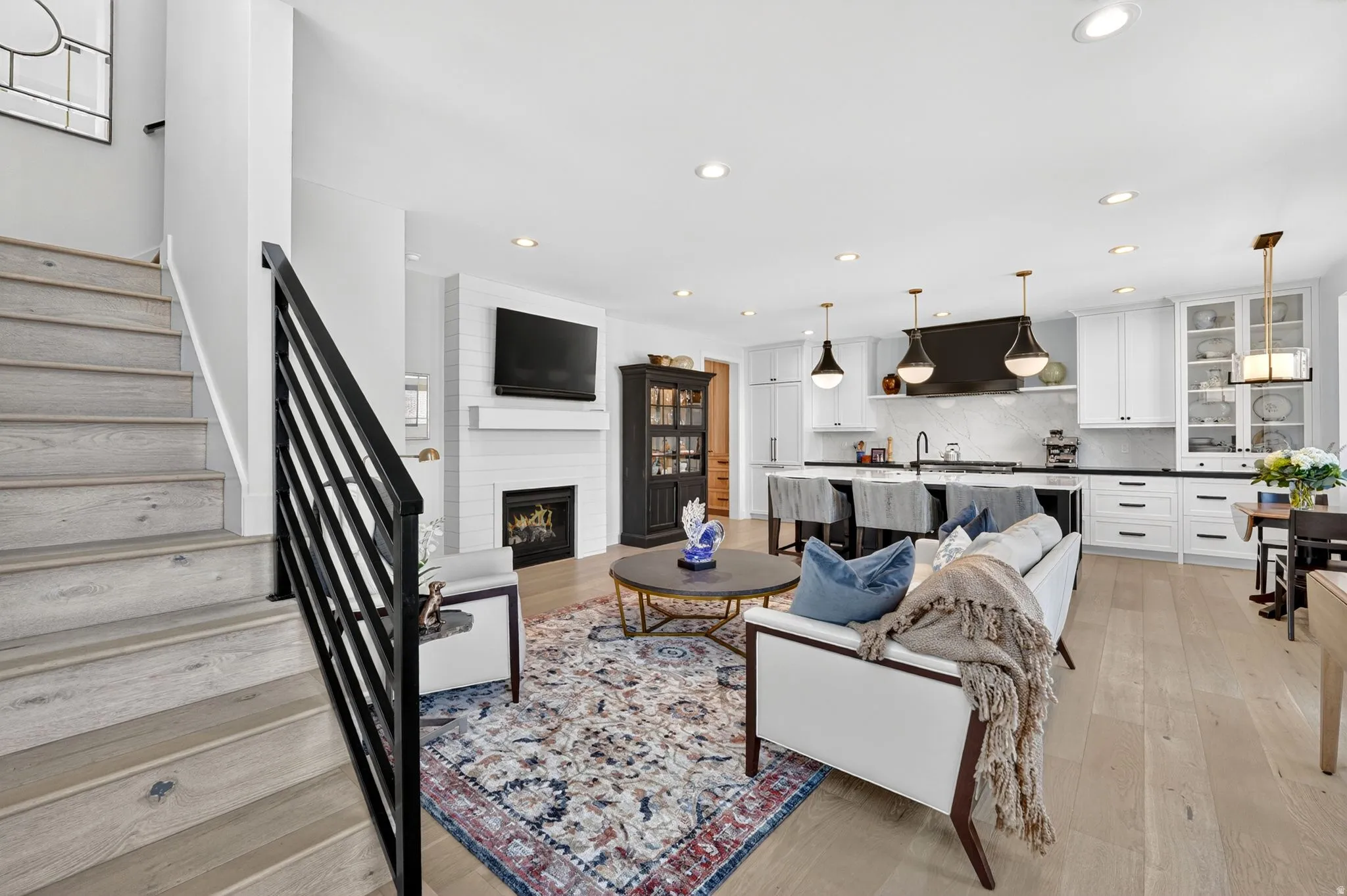 Living area with a large fireplace, light wood-type flooring, and recessed lighting