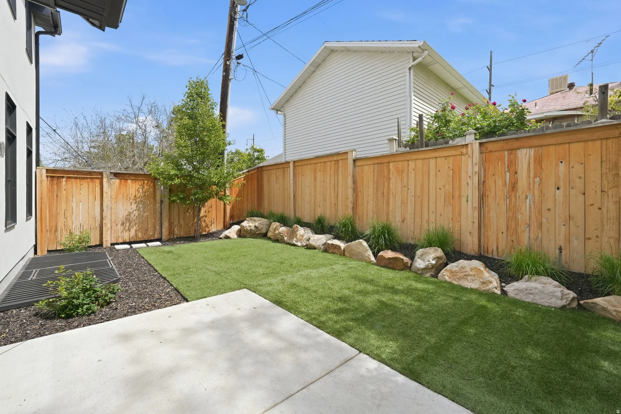 Fenced backyard featuring a patio and synthetic turf