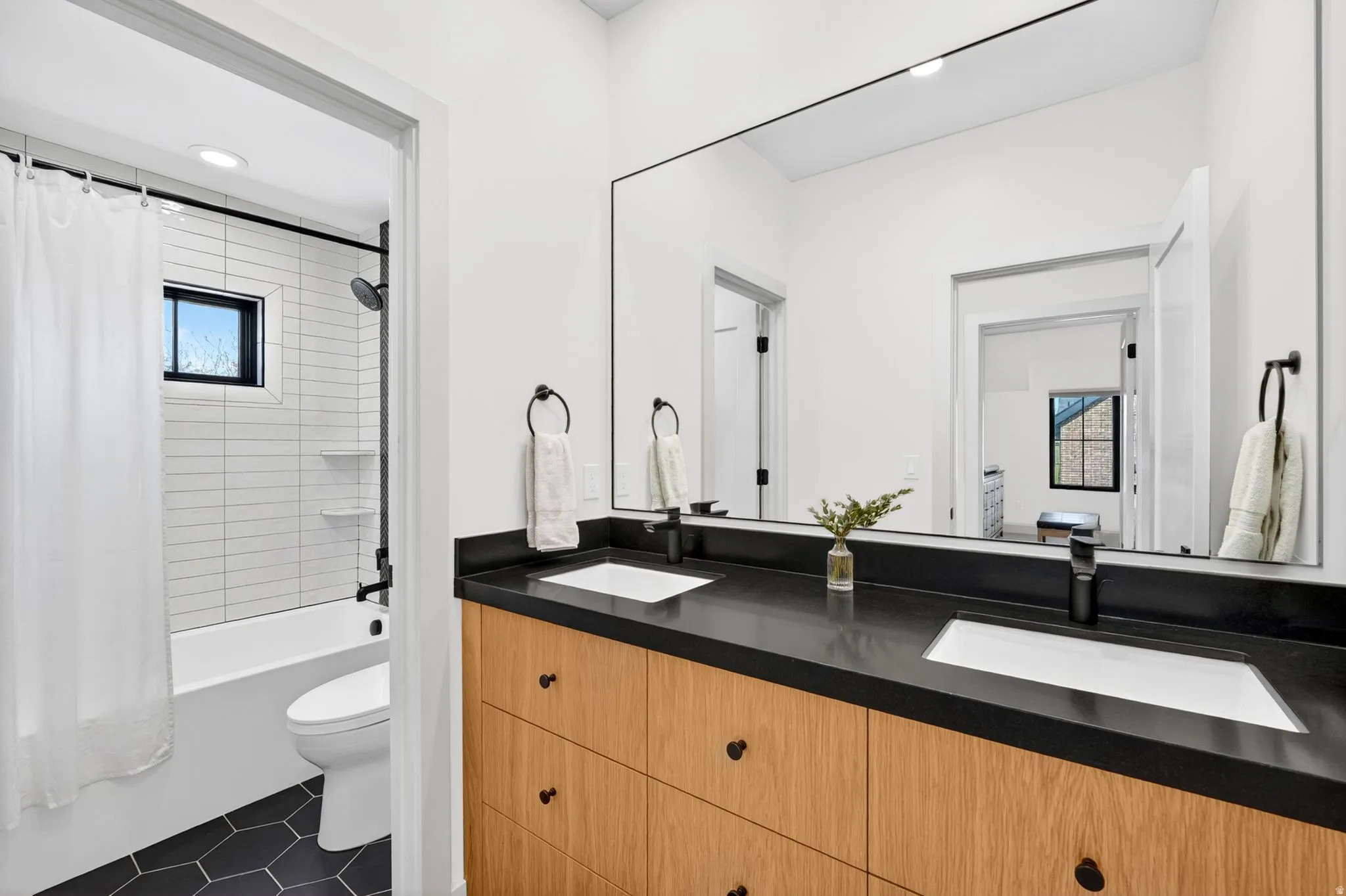 Full bath featuring double vanity, recessed lighting, shower / bath combo, and dark tile patterned flooring