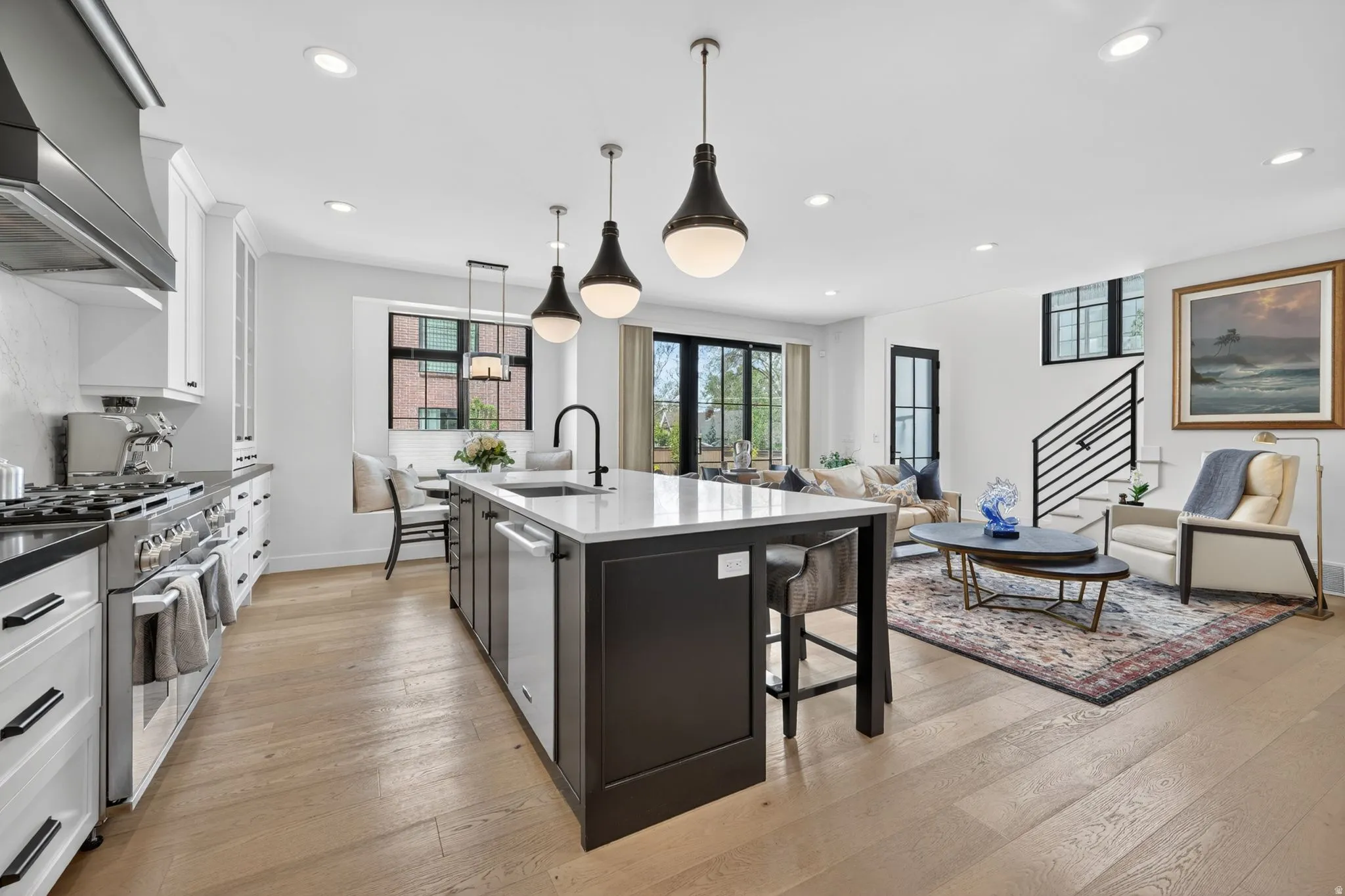 Two tone kitchen featuring two tone color scheme, open floor plan, stainless steel appliances, pendant lighting, and dark stone counters