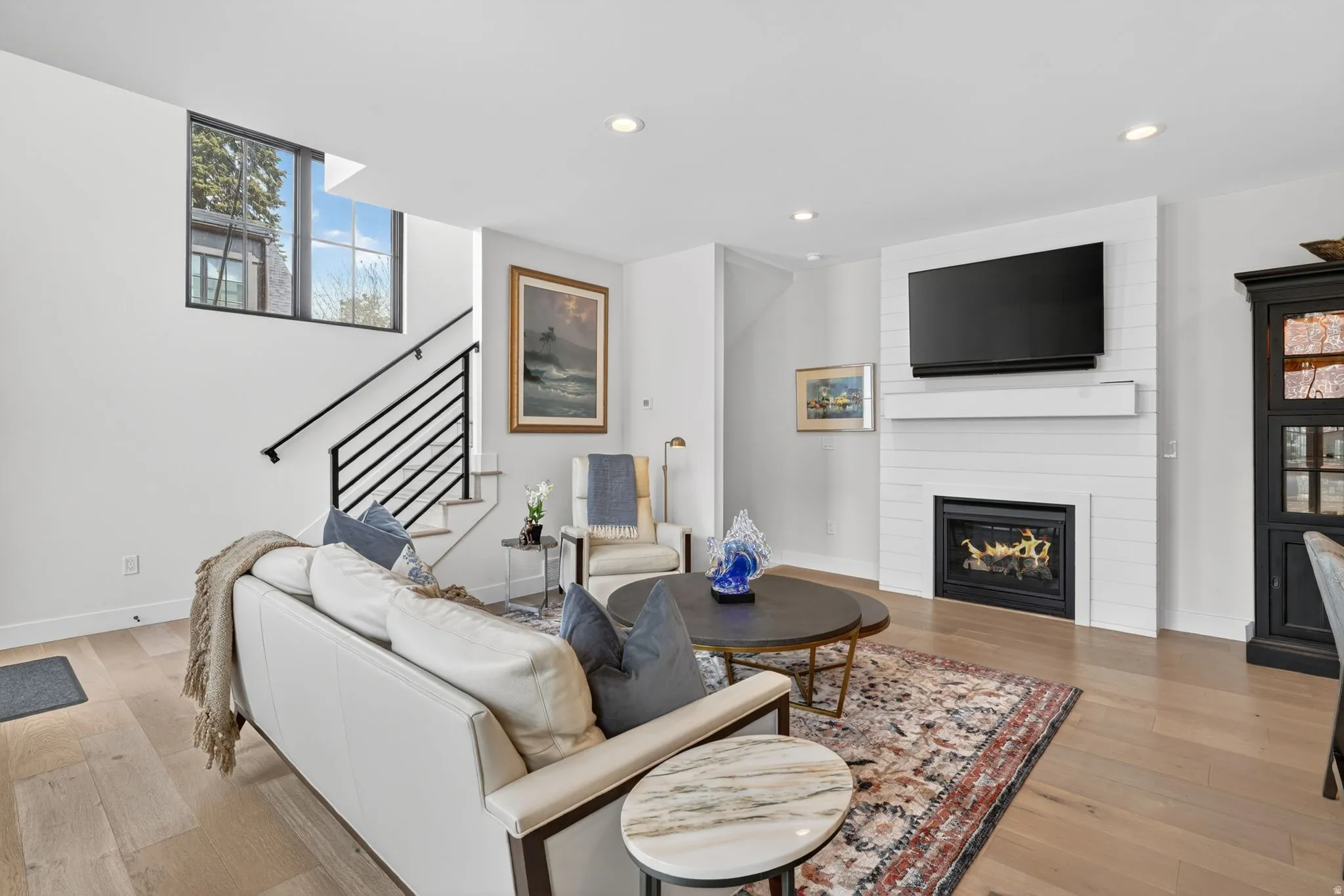 Living area featuring light wood-style flooring, recessed lighting, and a fireplace