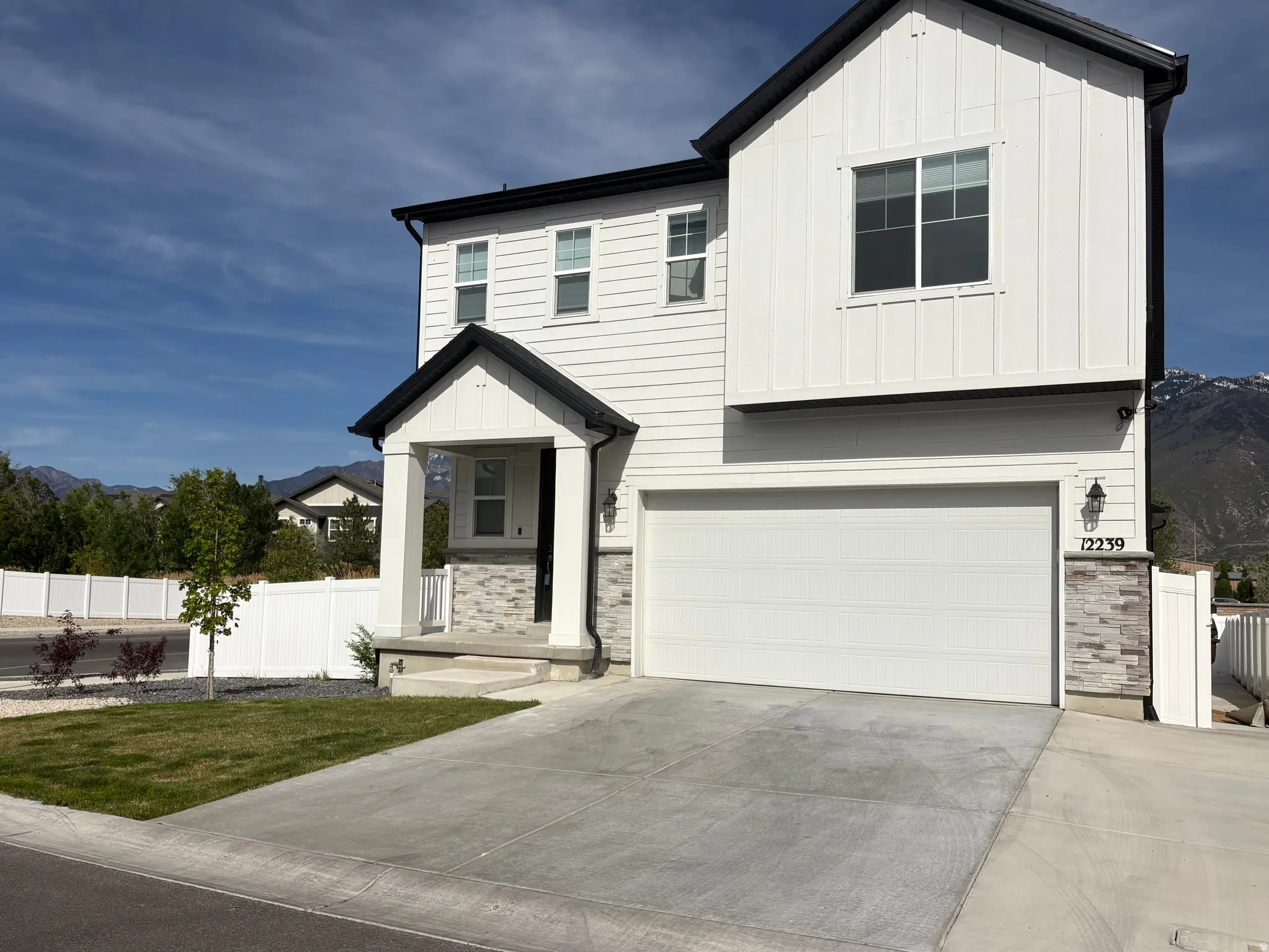 View of front of house featuring stone siding, board and batten siding, a garage, driveway, and a mountain view