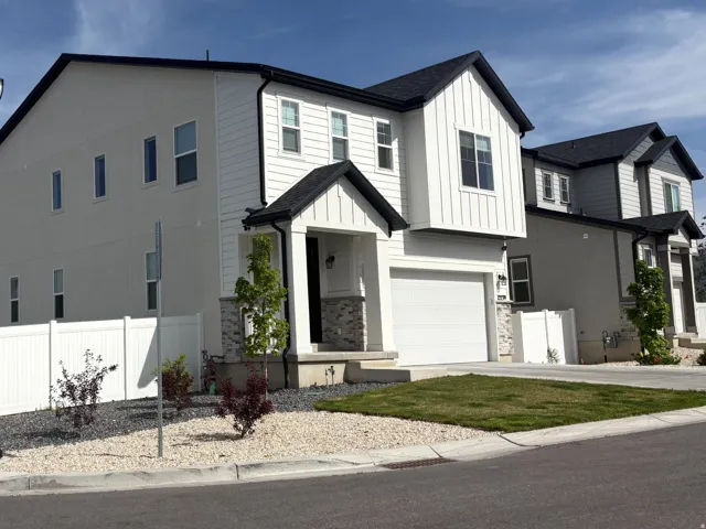 View of front of property featuring an attached garage, stone siding, driveway, a mountain view, and board and batten siding