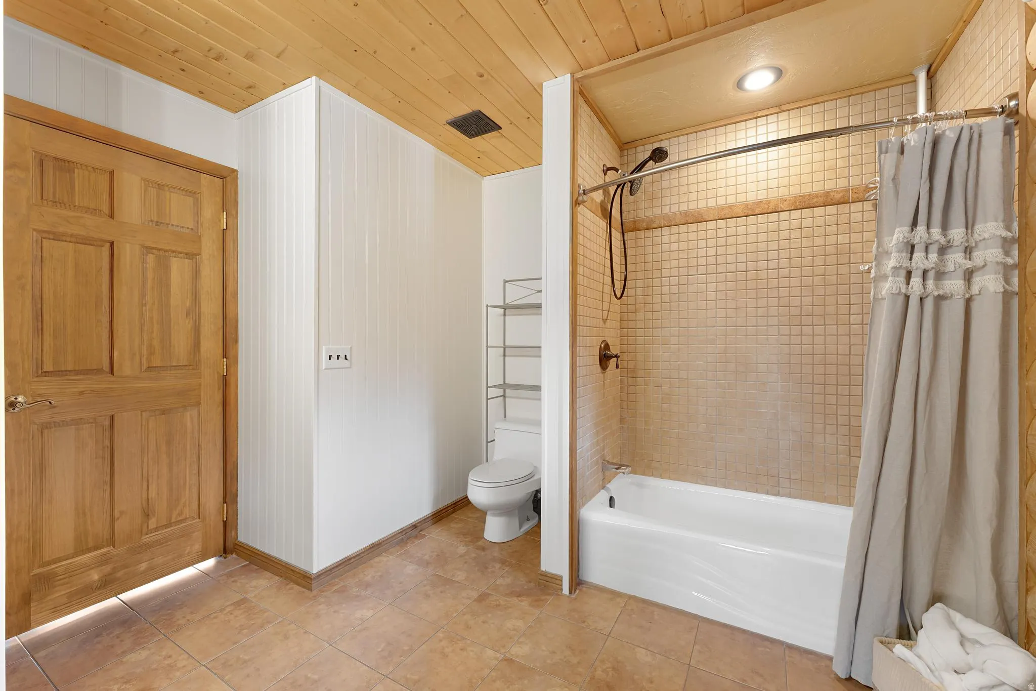 Bathroom featuring shower / bath combination with curtain, wooden ceiling, and light tile patterned floors