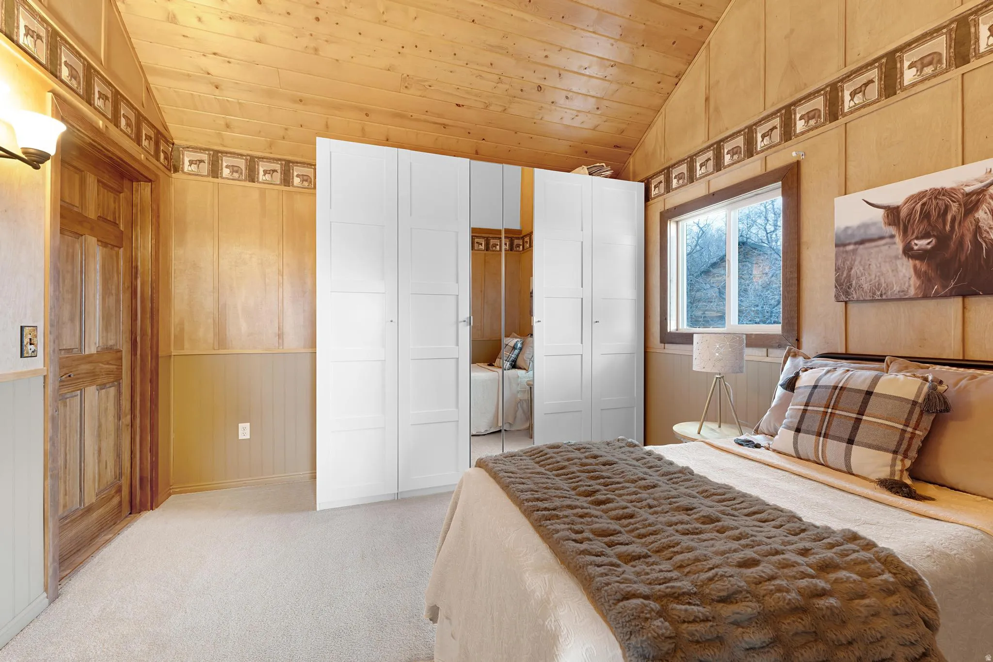 Bedroom featuring wood walls, light colored carpet, a wainscoted wall, a vaulted wood ceiling, and a decorative wall