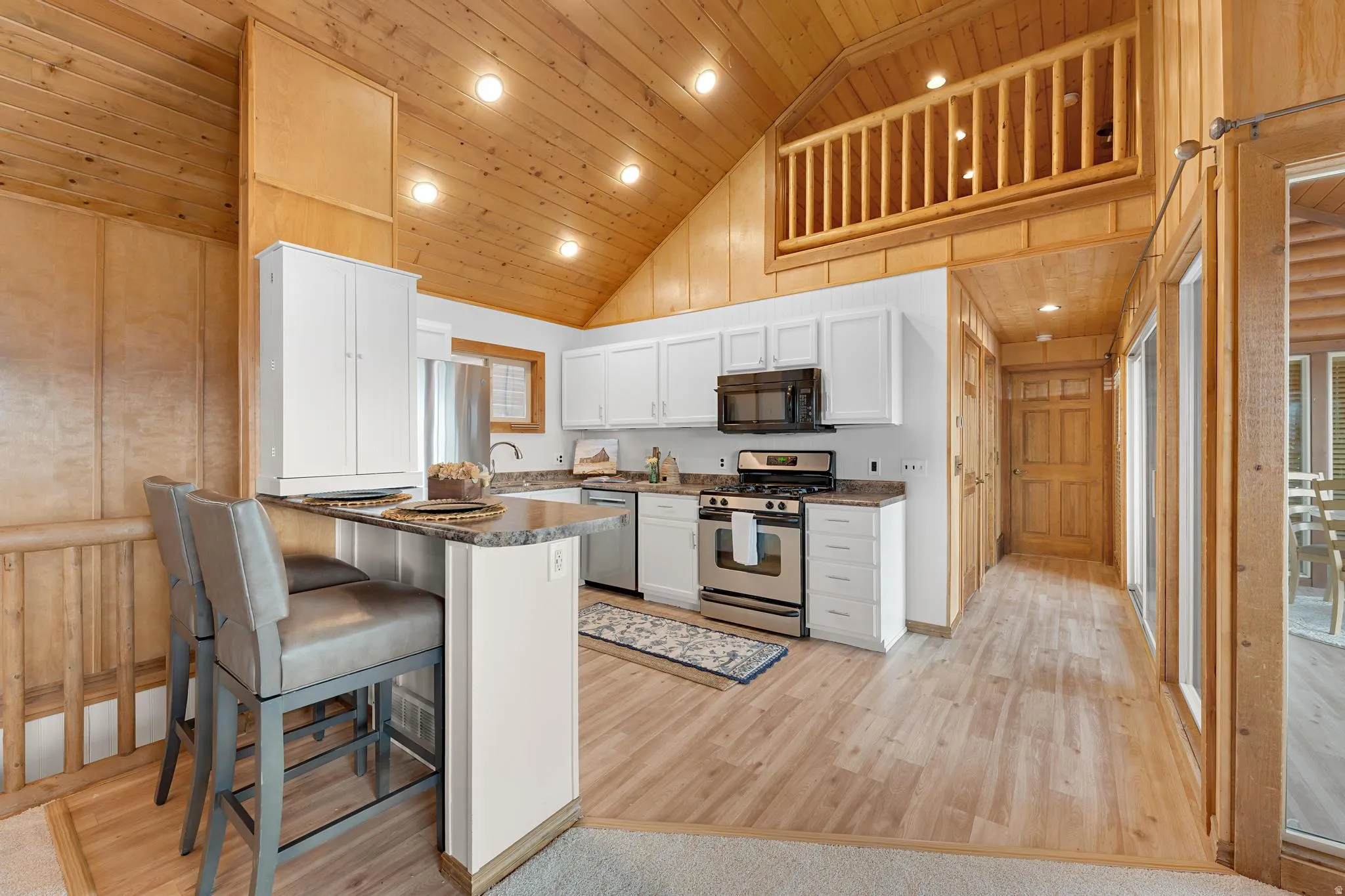 Kitchen featuring recessed lighting, dark countertops, stainless steel appliances, white cabinetry, and a vaulted wood ceiling