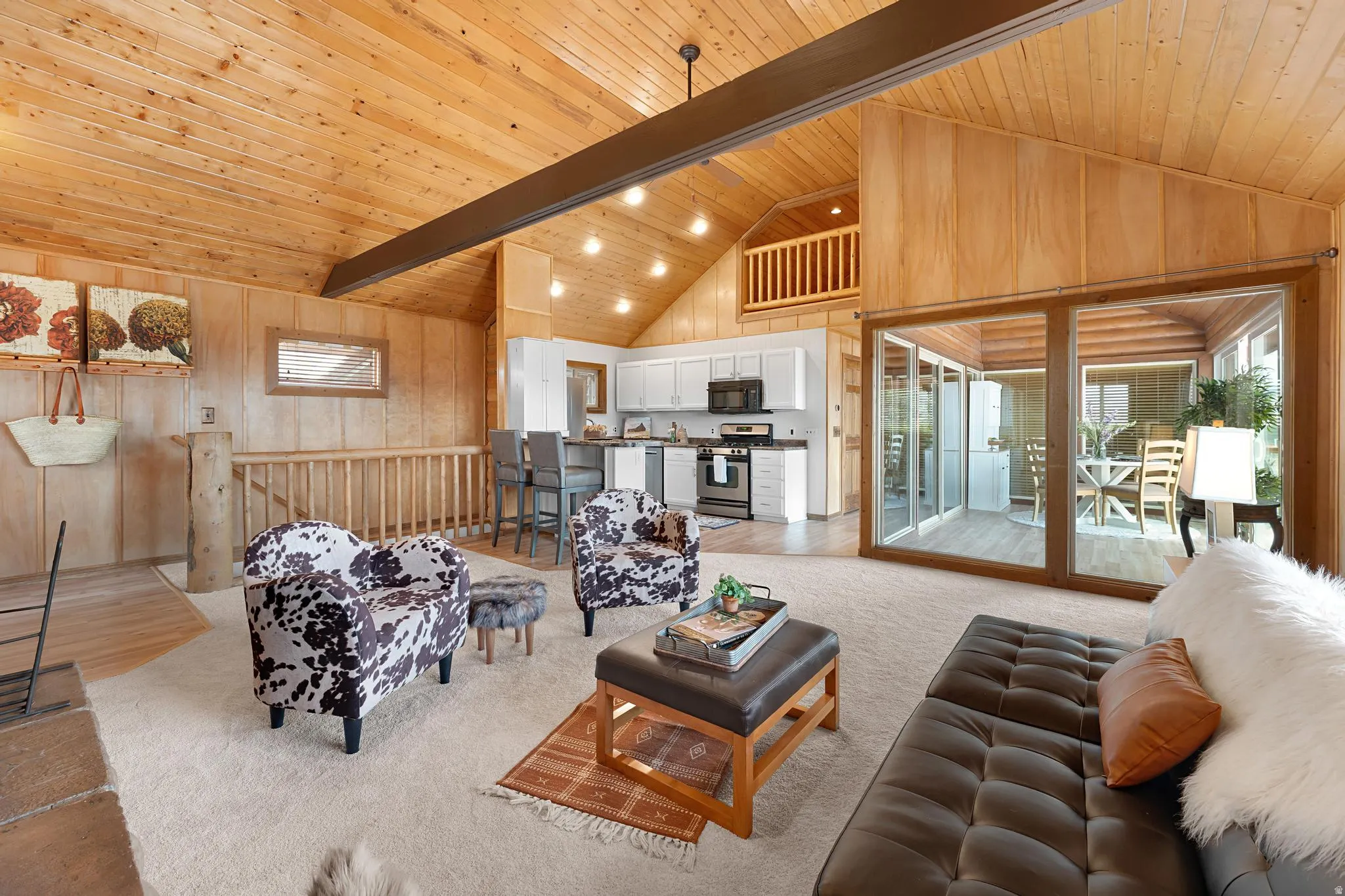 Living room featuring wooden walls, a high wood beamed ceiling, and light colored carpet