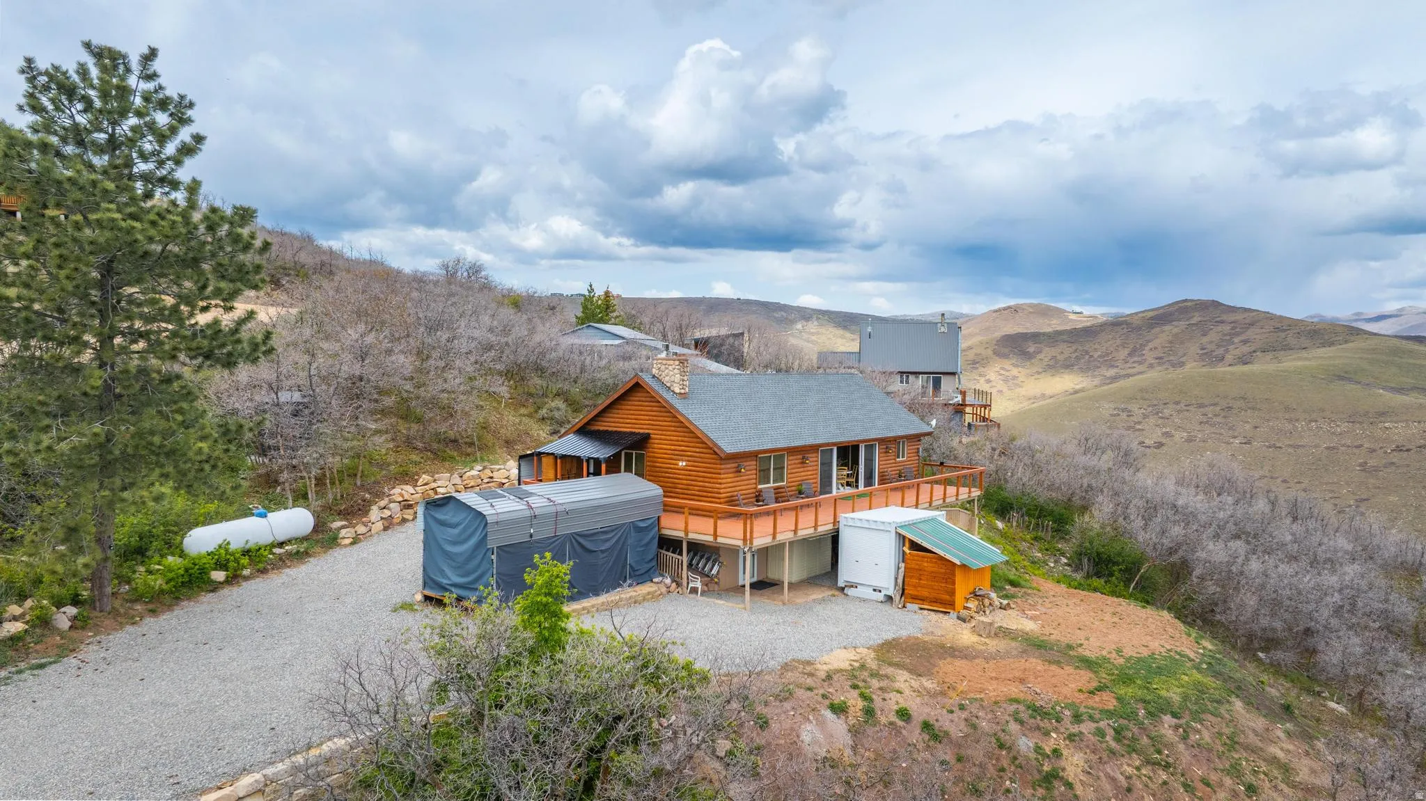 View of front of house featuring a deck with mountain view, log exterior, and an outdoor structure