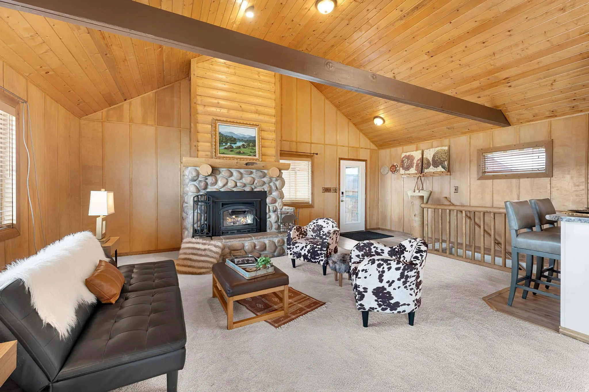 Carpeted living area featuring a fireplace, wooden walls, and vaulted ceiling