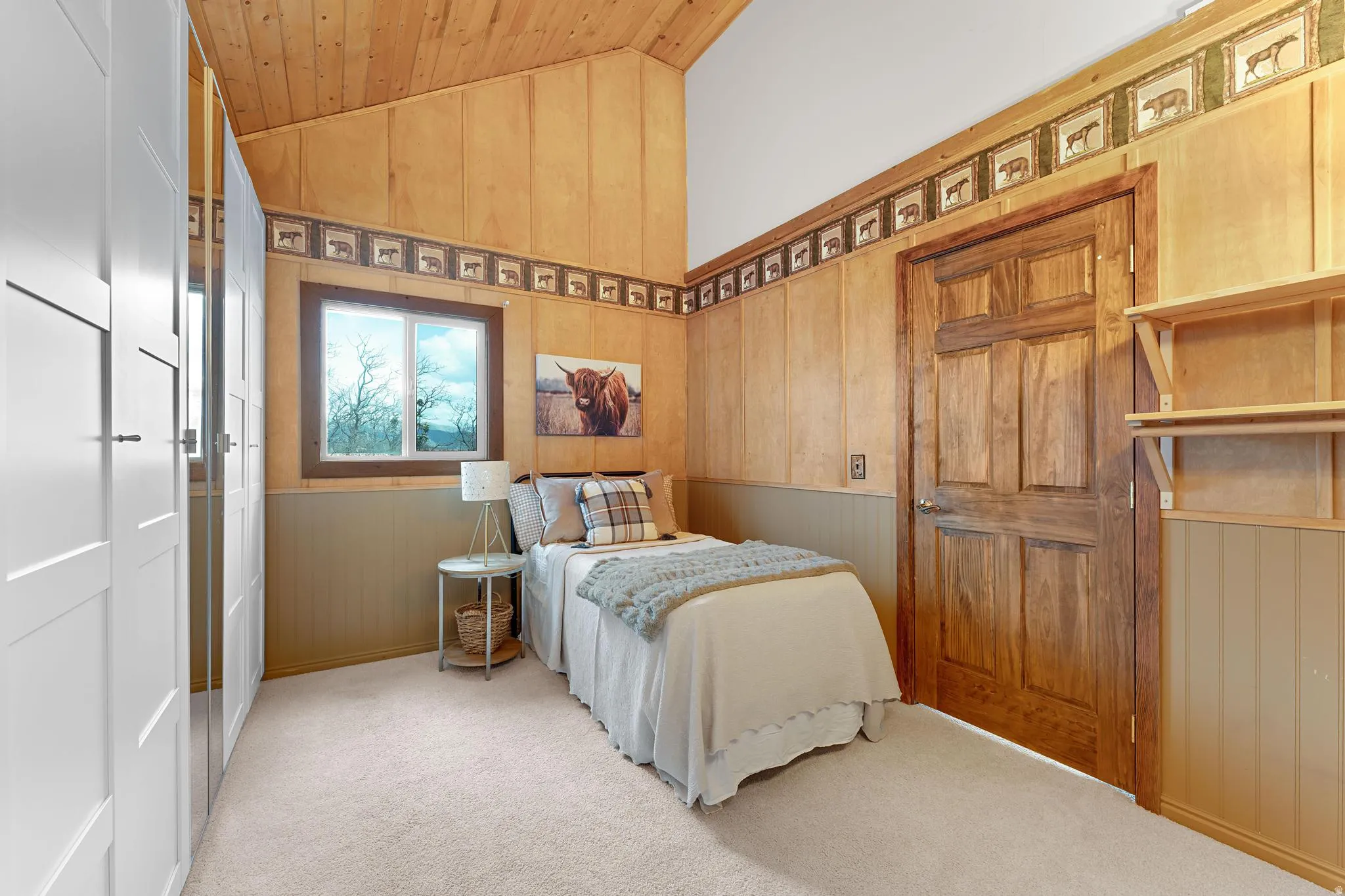 Bedroom featuring lofted ceiling, light colored carpet, wood walls, and wainscoting