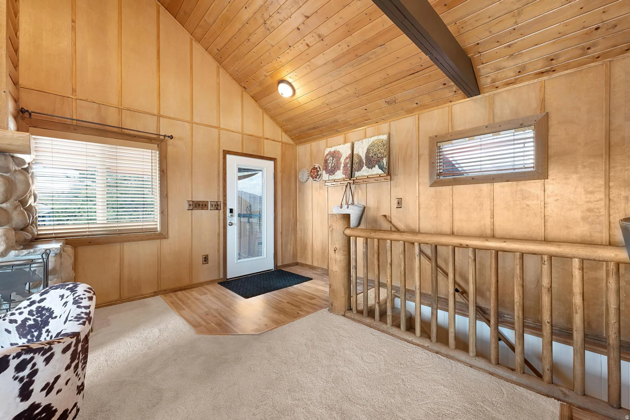Carpeted foyer entrance featuring plenty of natural light and a vaulted wood ceiling