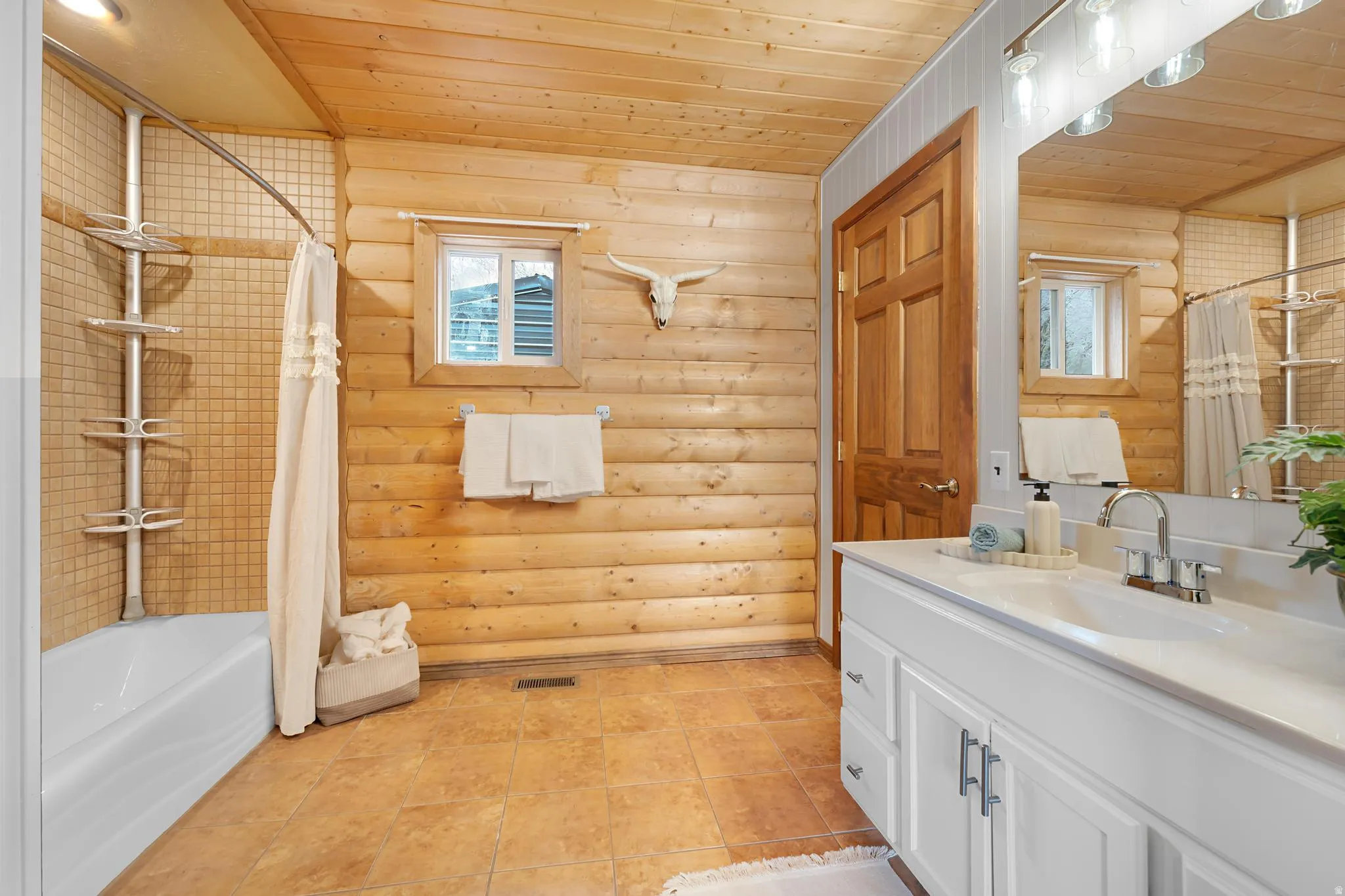 Full bathroom featuring wood ceiling, log walls, vanity, and shower / bath combo with shower curtain