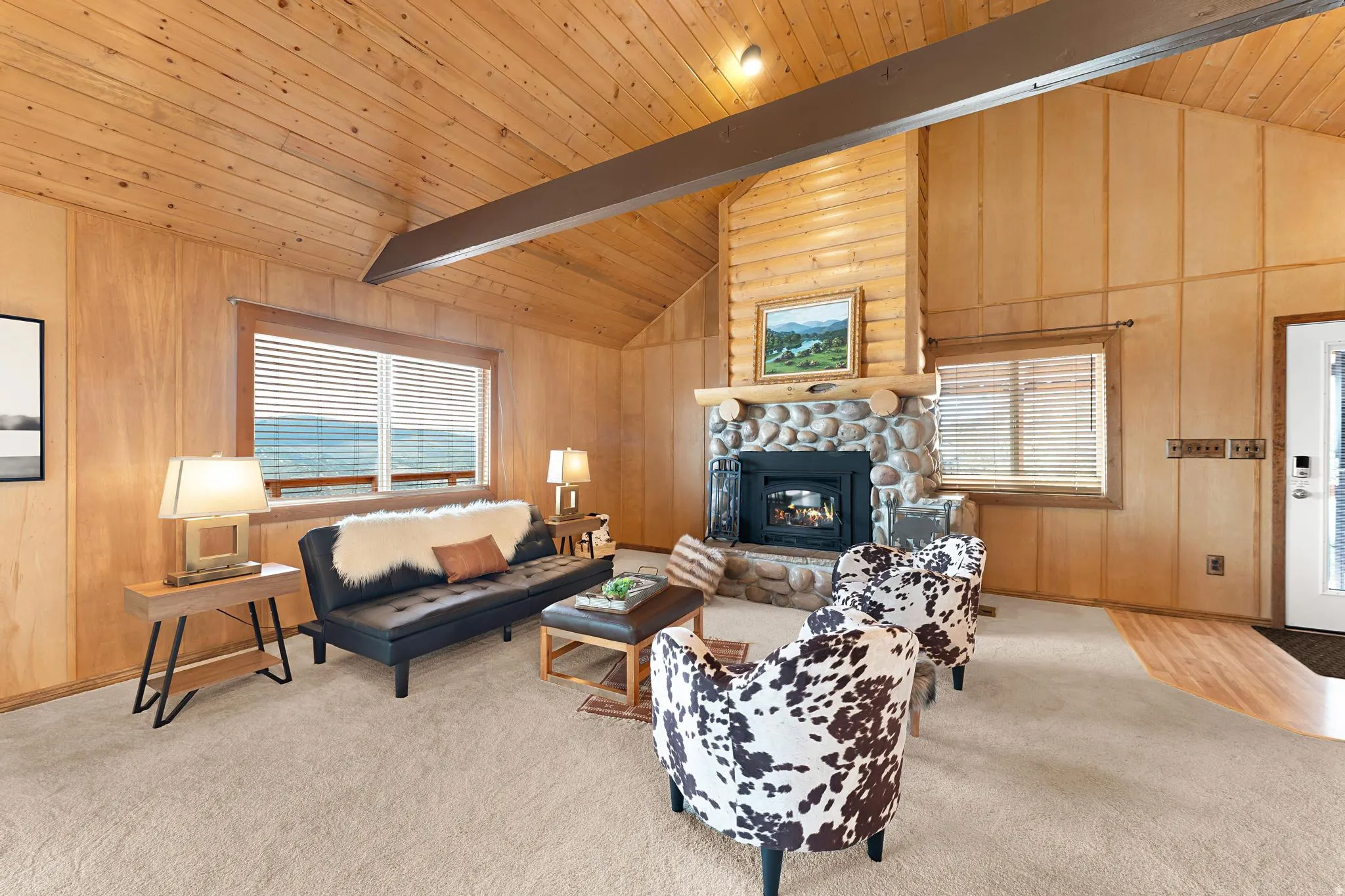 Living area with plenty of natural light, carpet floors, a high wood beamed ceiling, and a stone fireplace